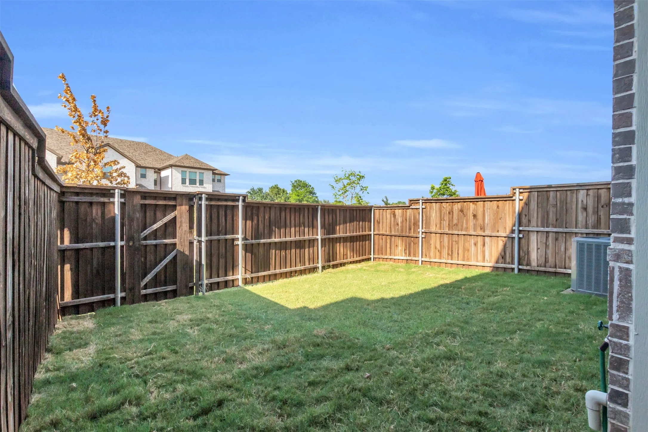 Fenced backyard featuring a grassy lawn, wood privacy fencing, and a side gate