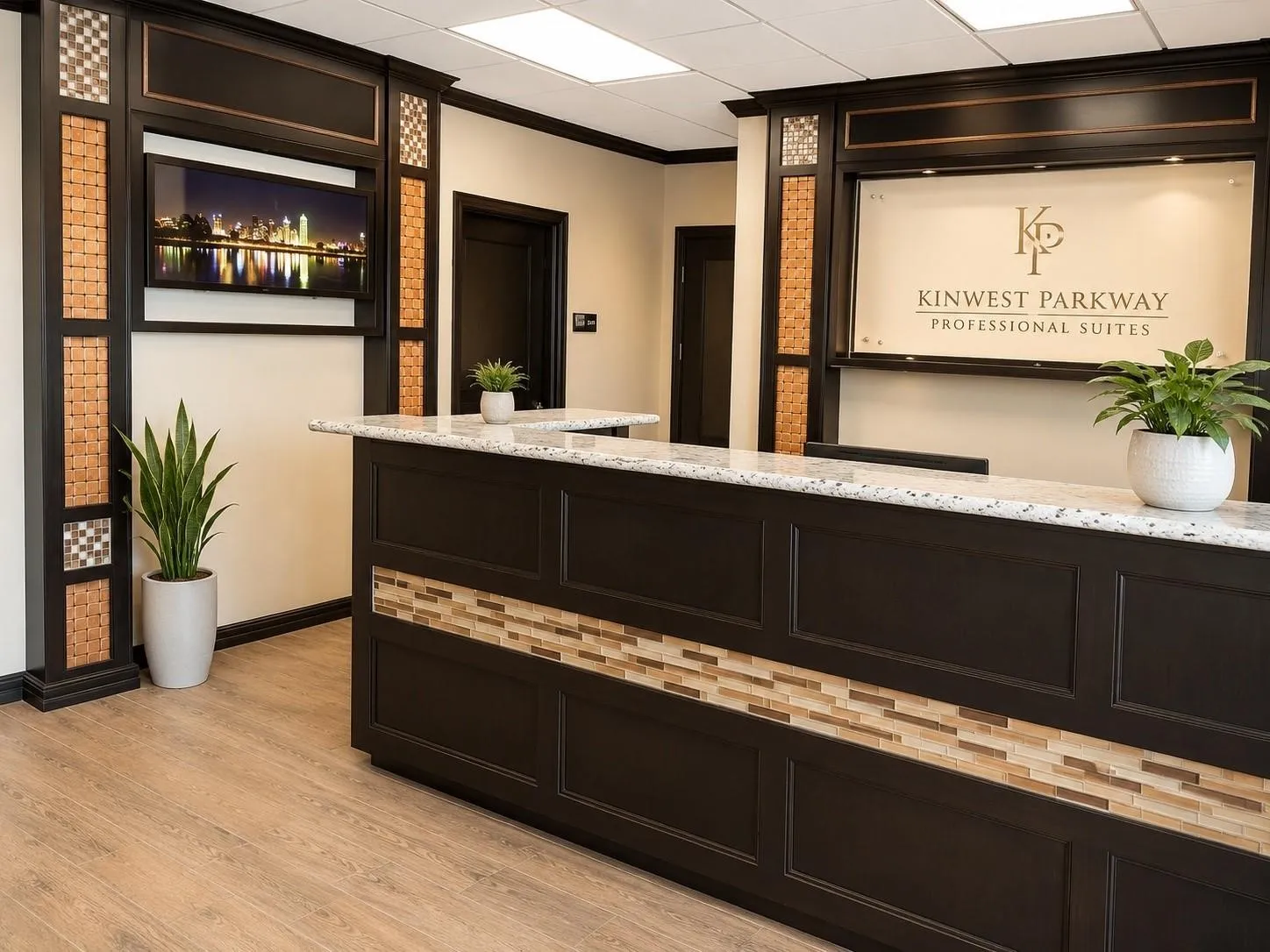 Reception counter with a light-toned speckled countertop, dark wood-finish cabinetry, and a mosaic tile accent band