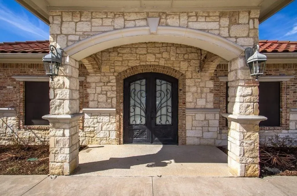 Stone and brick facade featuring a covered entryway with an arched detail