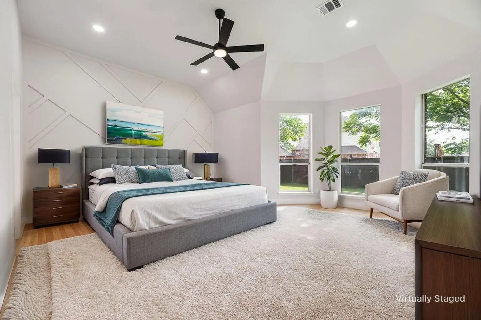 Vaulted ceiling with recessed lighting and ceiling fan, accent wall with geometric paneling, bay window configuration, and wood-finish flooring
