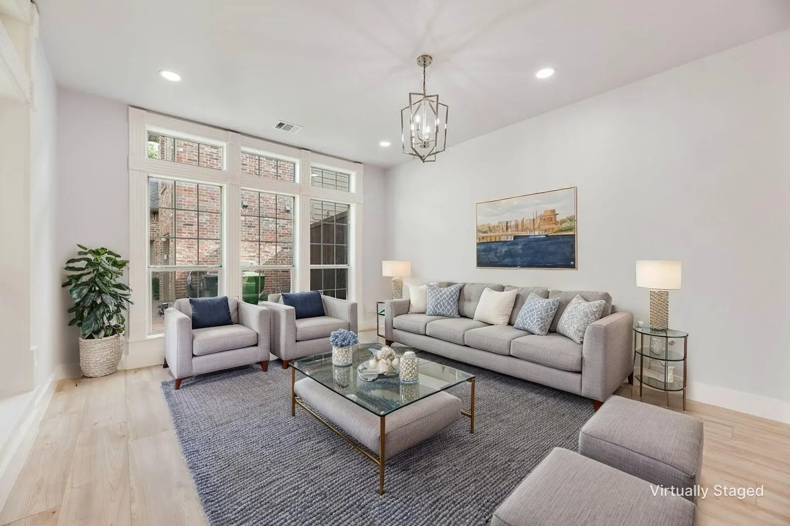 Expansive windows with transom details, wood-finish flooring, recessed lighting, and a prominent decorative chandelier