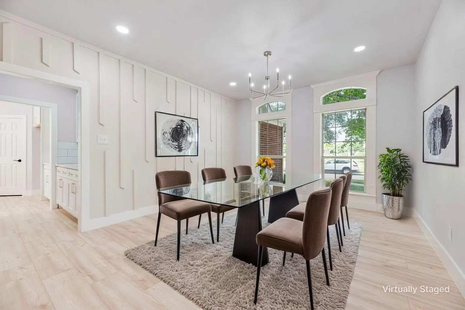 Recessed lighting, wood-finish flooring, accent wall paneling, arched window trim, and a modern chandelier
