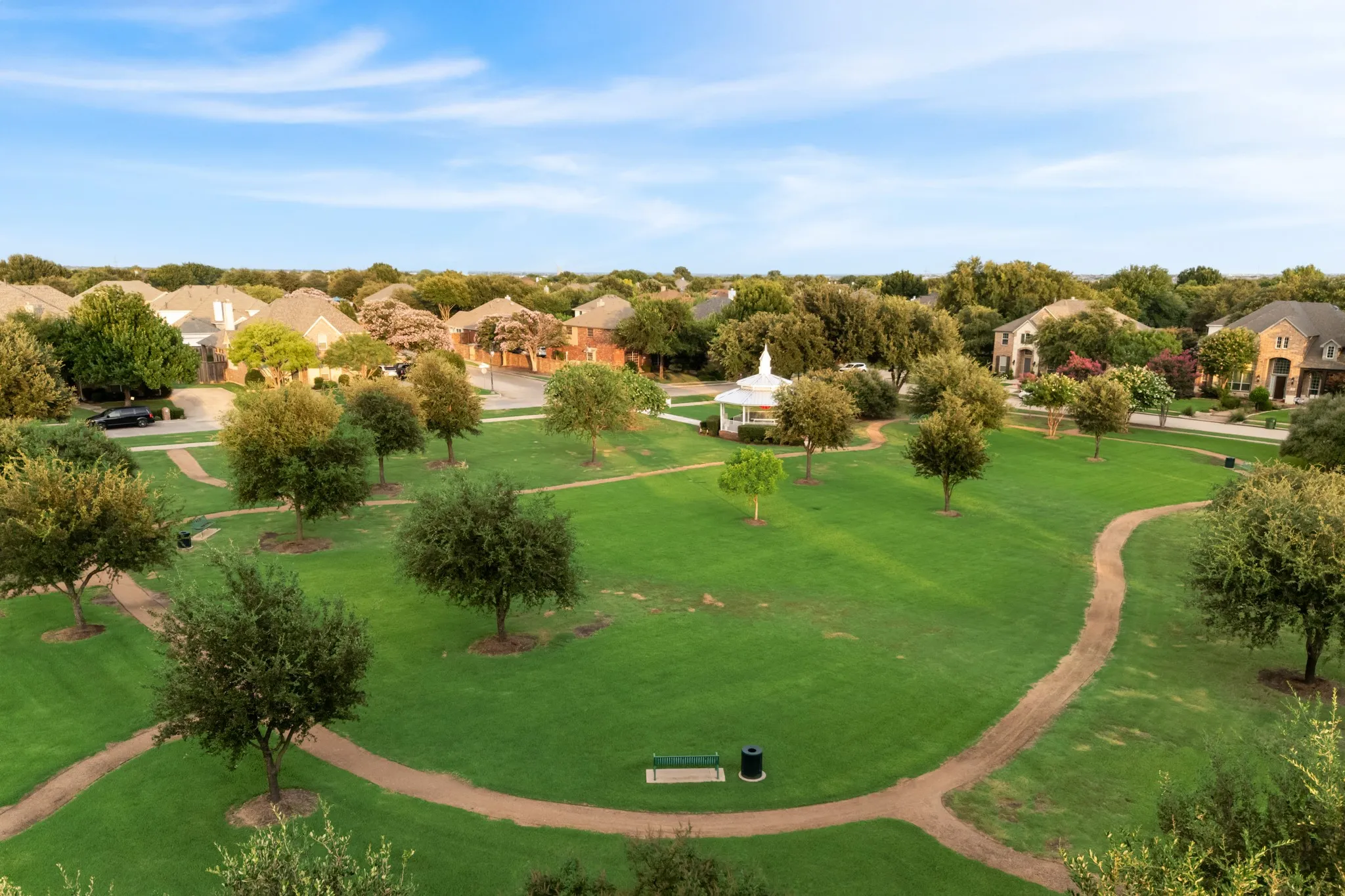 Expansive green space featuring a white gazebo, meandering walking paths, and numerous mature trees