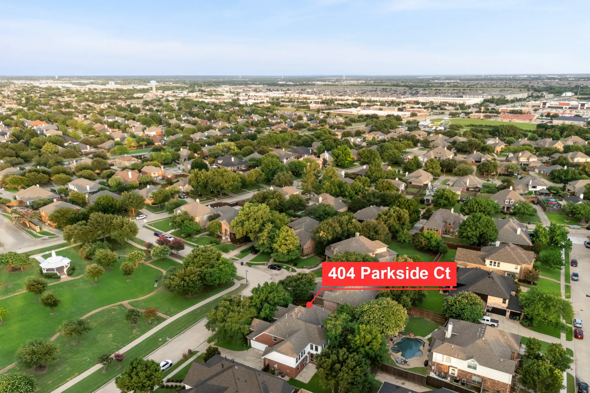 Aerial perspective showcasing a residential neighborhood with numerous single-family homes, mature trees, and a distant water tower