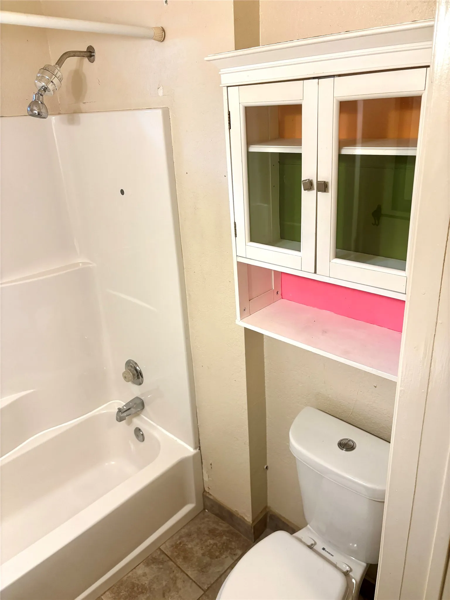 White porcelain toilet with a matching built-in cabinet featuring glass panel doors and open shelving
