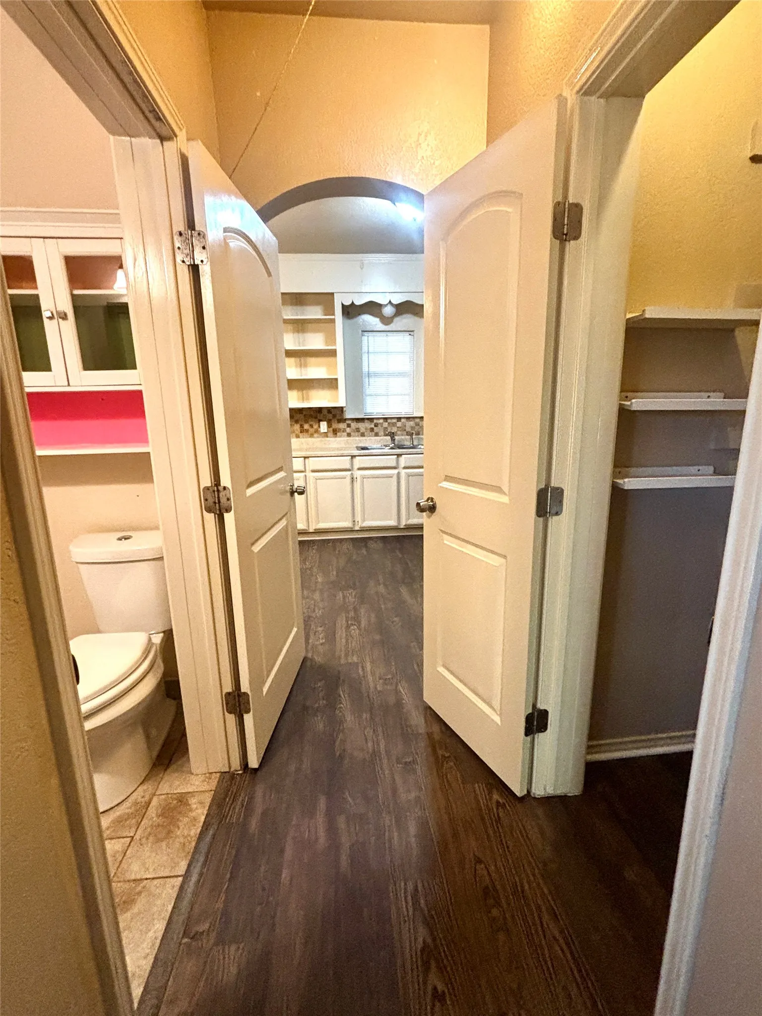 Dark wood-finish flooring extending through an arched entryway