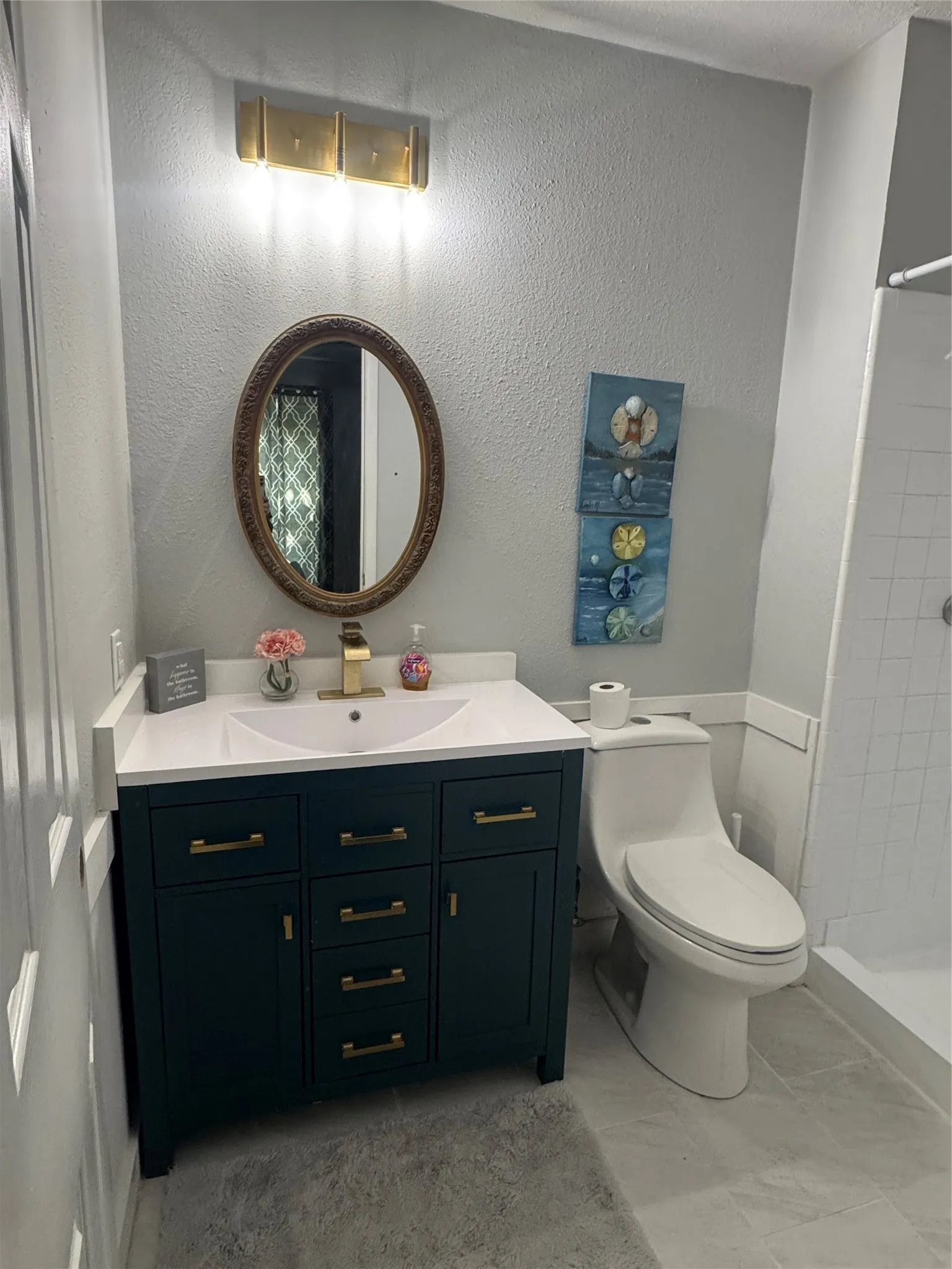 Vanity with white countertop and integrated sink, gold-tone faucet, and oval mirror