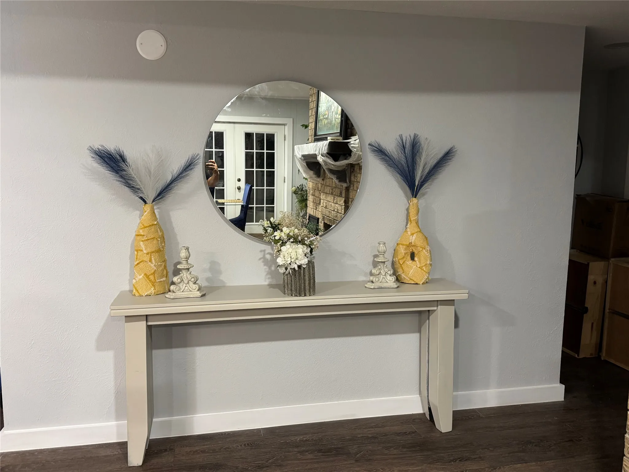 Wood-finish flooring with white baseboards, light-toned walls, and a round wall mirror