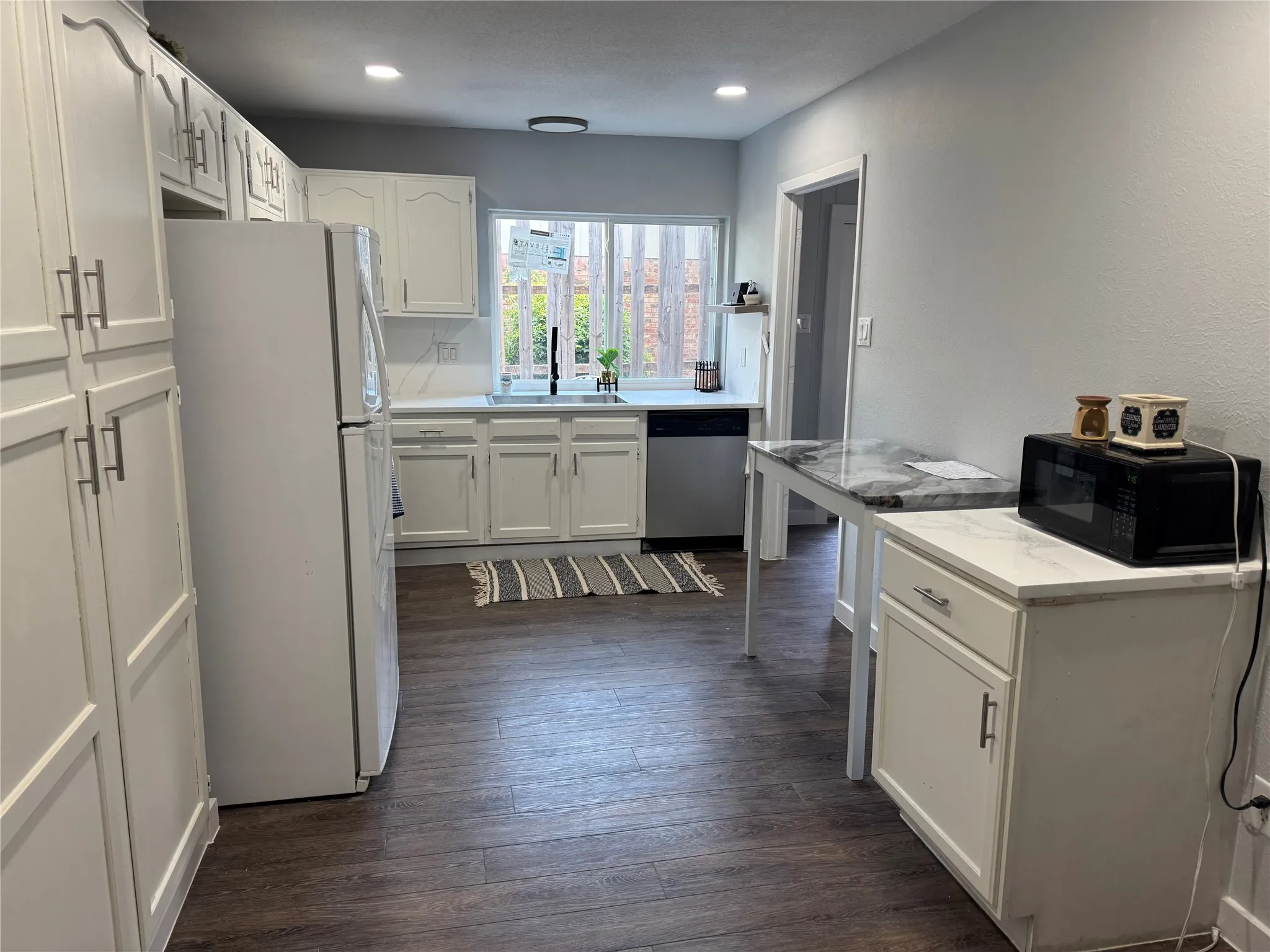 Kitchen featuring extensive white cabinetry, wood-finish flooring, recessed lighting, and solid surface countertops