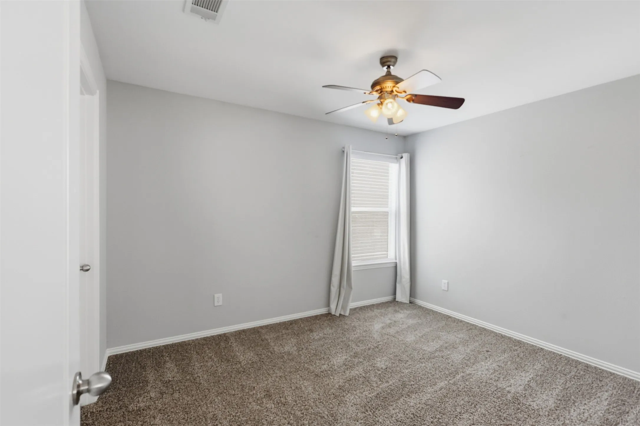 Spacious room with plush carpet flooring, light gray wall paint, and white trim molding
