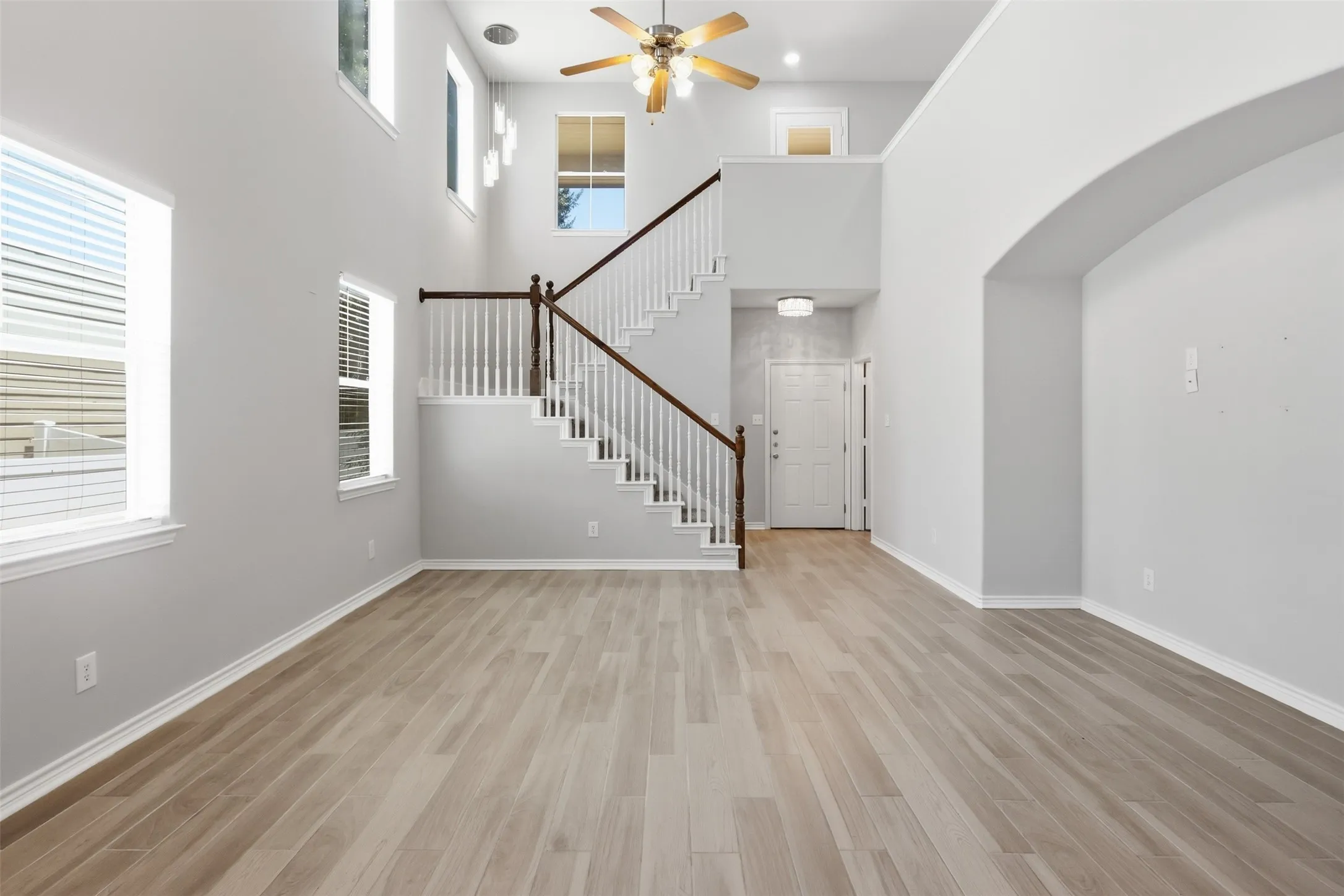 Two-story living area featuring wood-finish flooring and a vaulted ceiling with a ceiling fan
