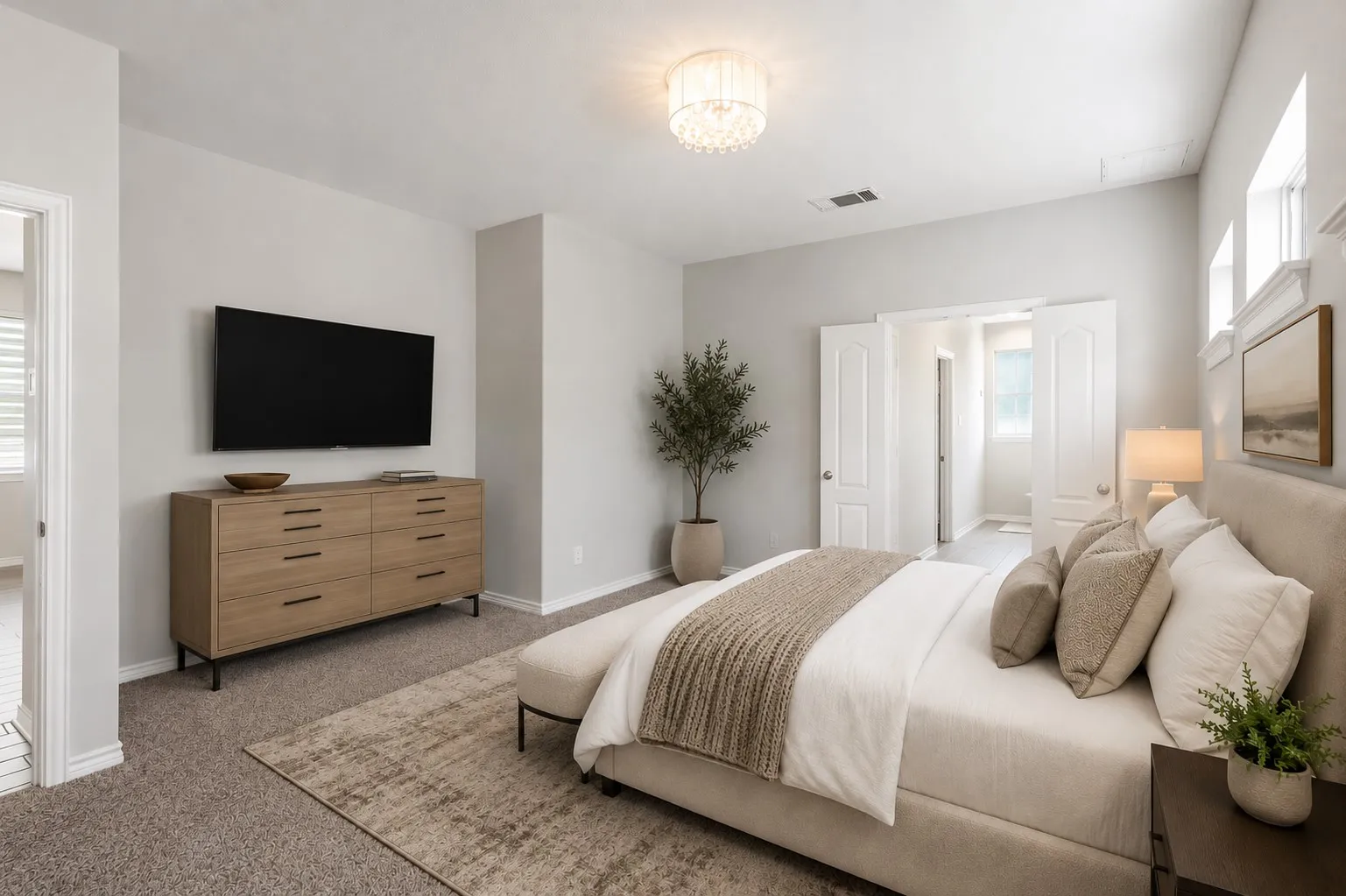 Spacious bedroom featuring carpet flooring, neutral wall tones, a modern chandelier, and double doors opening to an adjoining room