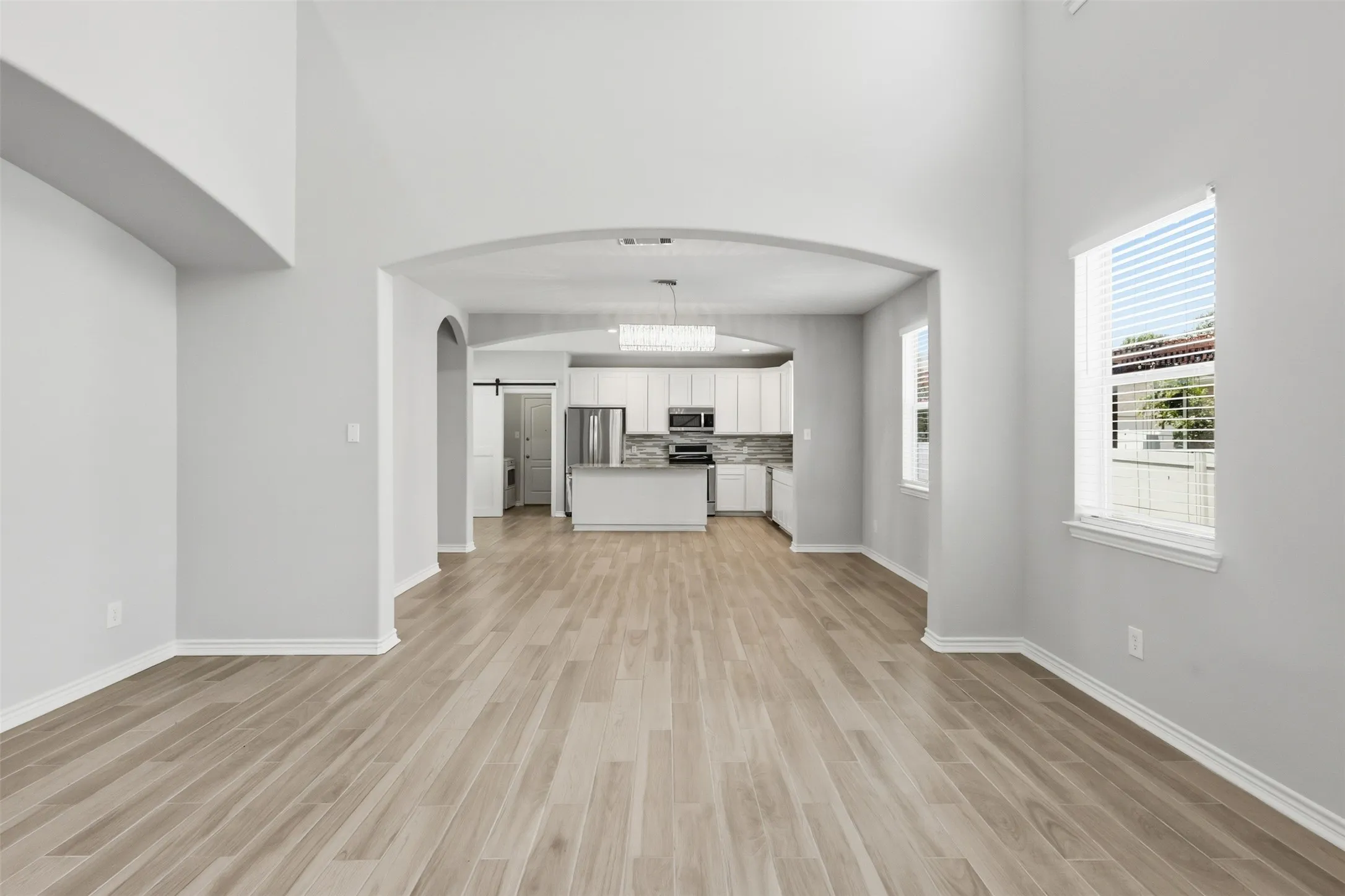Spacious living area featuring wood-finish flooring, high ceilings, and light gray wall tones