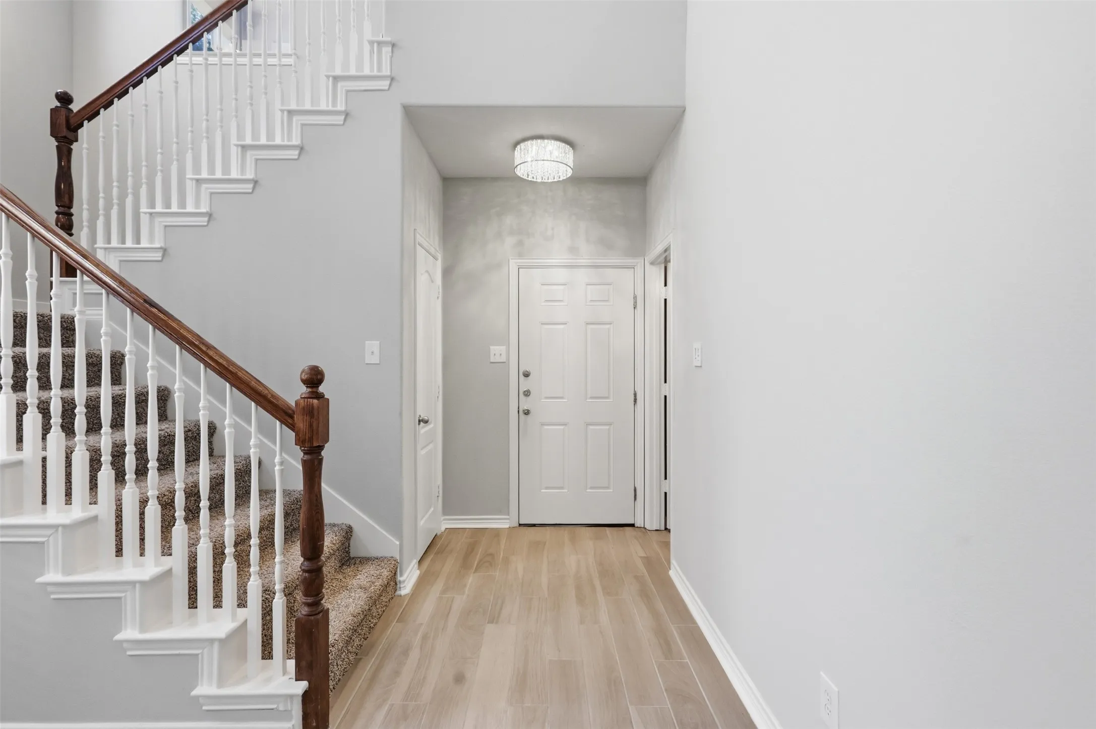 Foyer entrance featuring wood-finish flooring, a white paneled door, and a flush mount light fixture