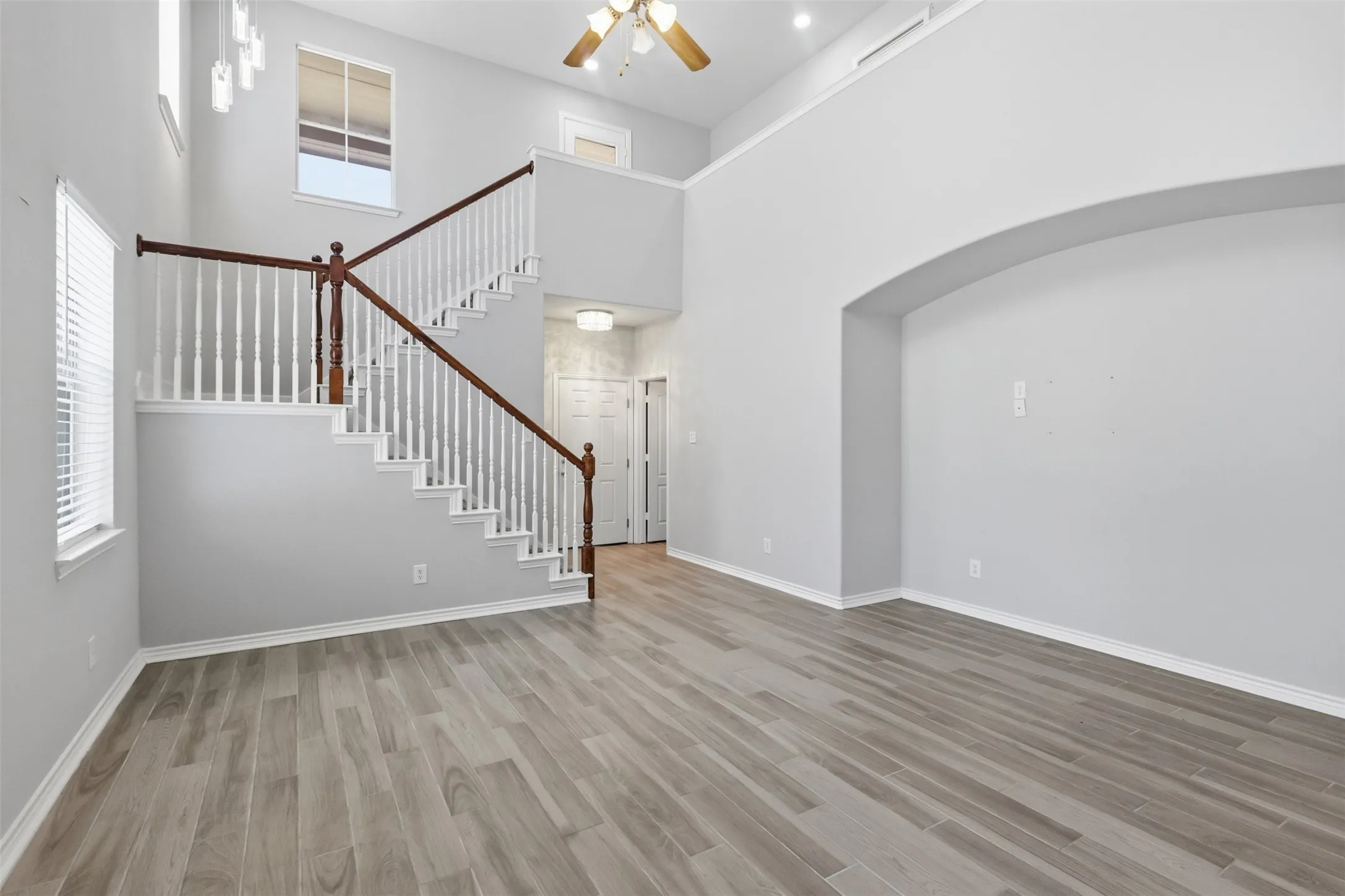 Two-story open-concept entry featuring a staircase with white spindles and a dark wood-finish handrail