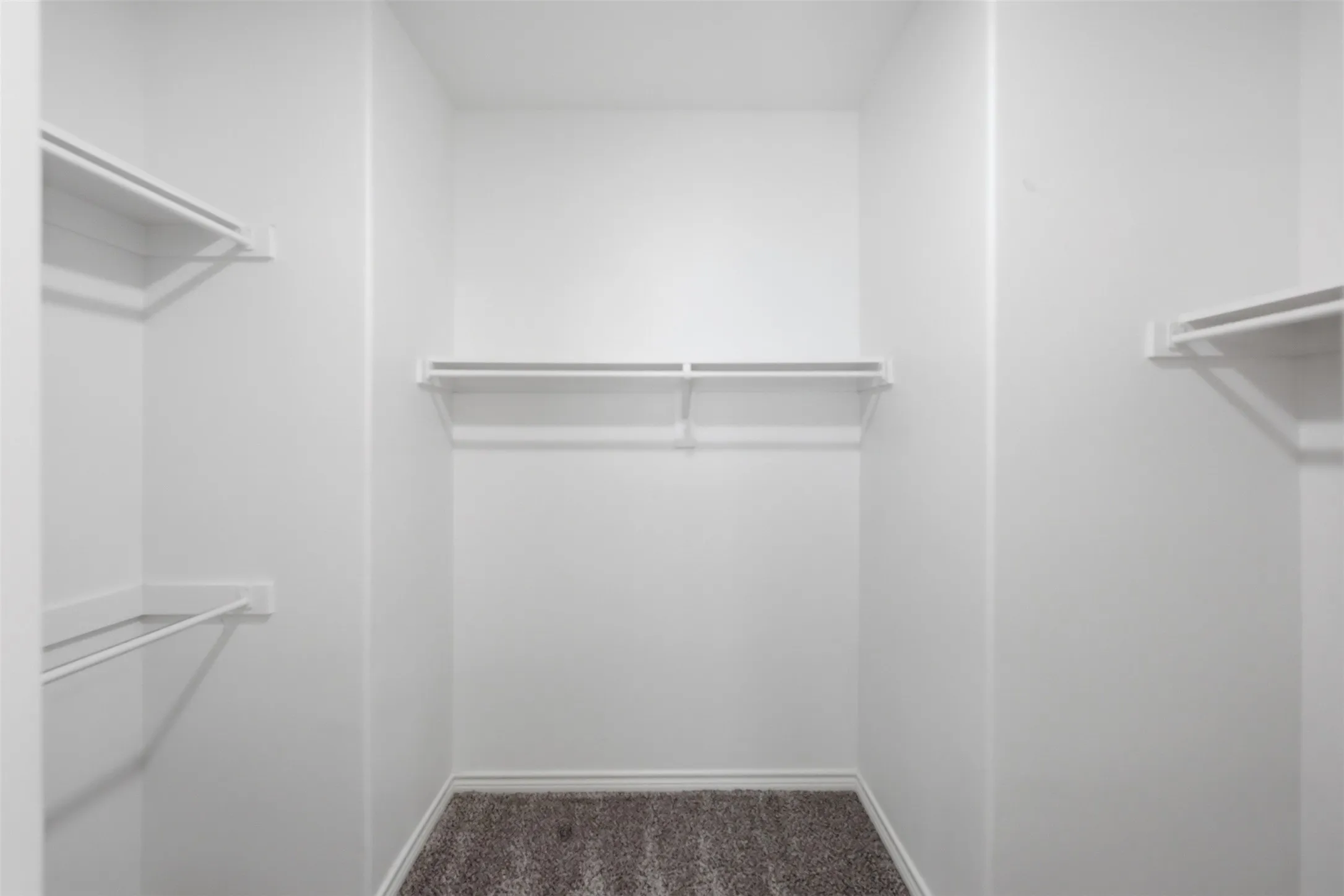 Walk-in closet featuring white wire shelving and hanging rods