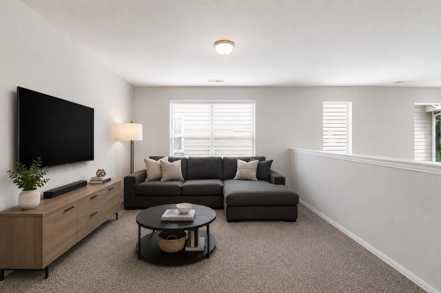 Carpeted loft area featuring a low wall partition, multiple windows with horizontal blinds, and a flush mount ceiling light