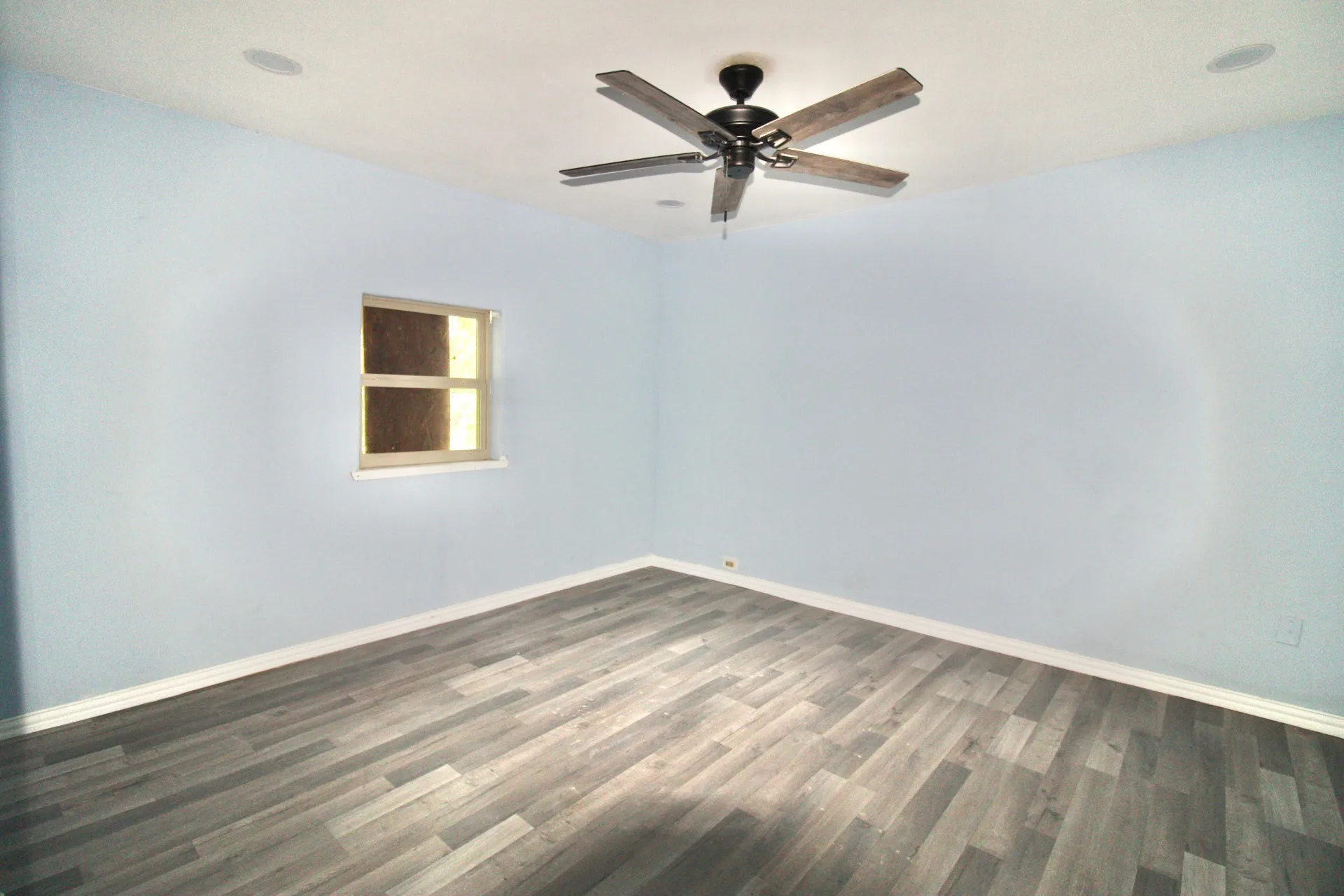 Spacious room featuring wood-finish flooring, a contemporary ceiling fan, and recessed lighting