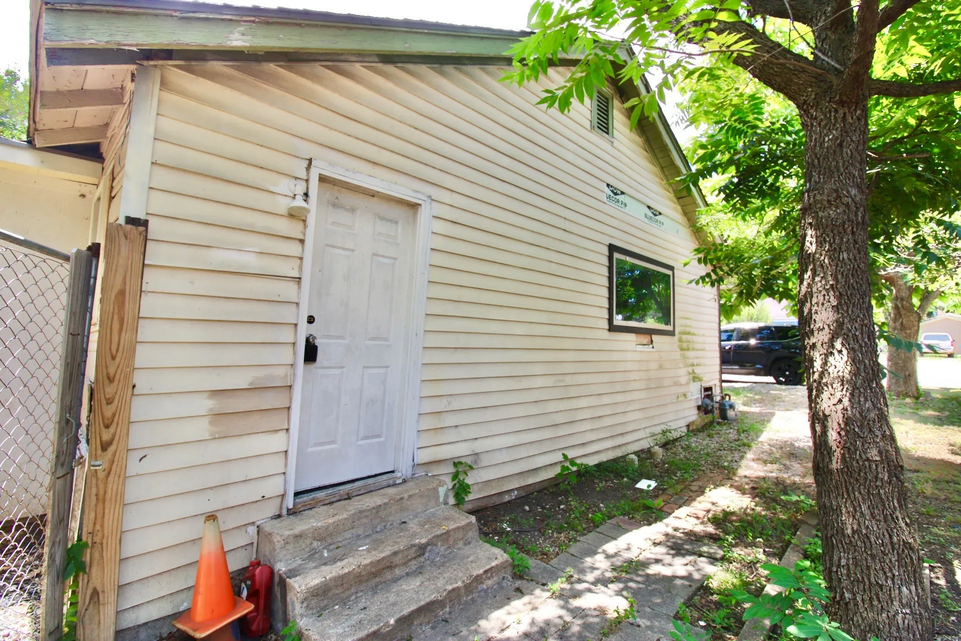 Siding exterior featuring a side door with concrete steps and a single window
