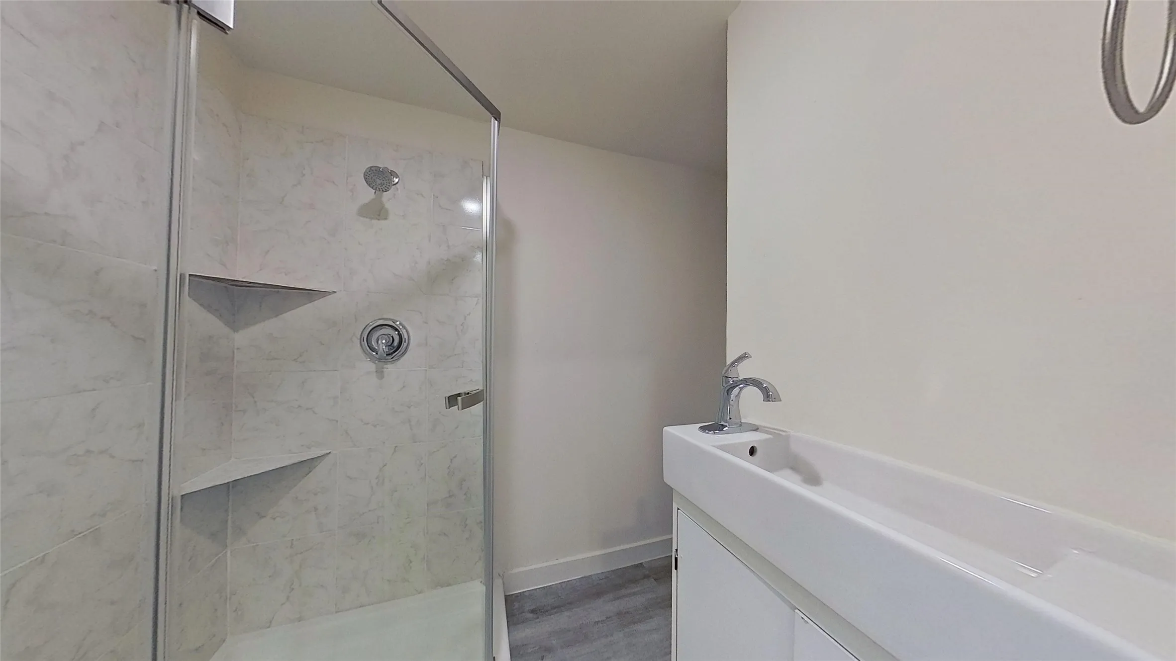 Walk-in shower with clear glass enclosure and integrated shelving