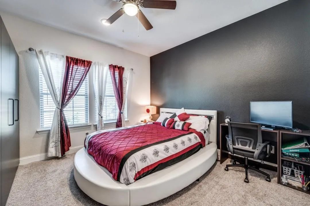 Carpeted room featuring a dark accent wall and three windows with blinds