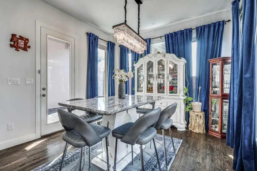 Dining area featuring dark wood-finish flooring, white walls, and a glass-paneled door