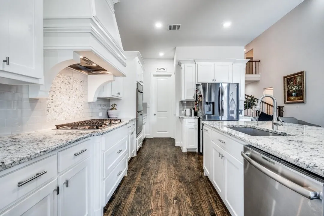 Kitchen featuring white cabinetry, granite countertops, stainless steel appliances, a tile backsplash, and dark wood-finish flooring