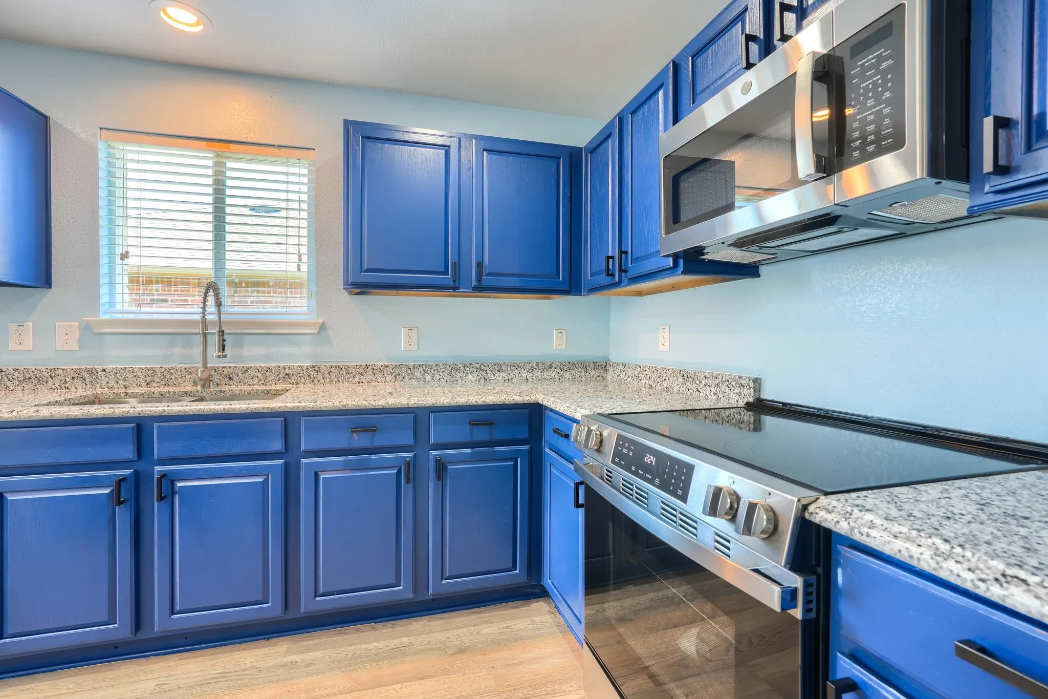 Kitchen featuring blue cabinetry, speckled countertops, stainless steel electric range, and stainless steel microwave