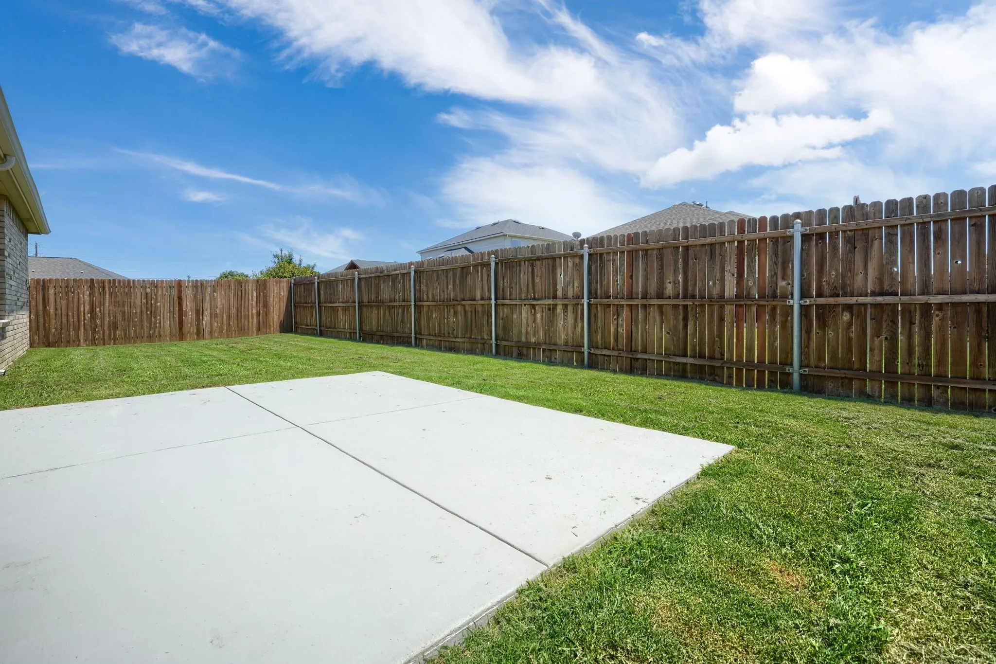 Expansive backyard featuring a concrete patio, a generous grassy area, and a wood privacy fence