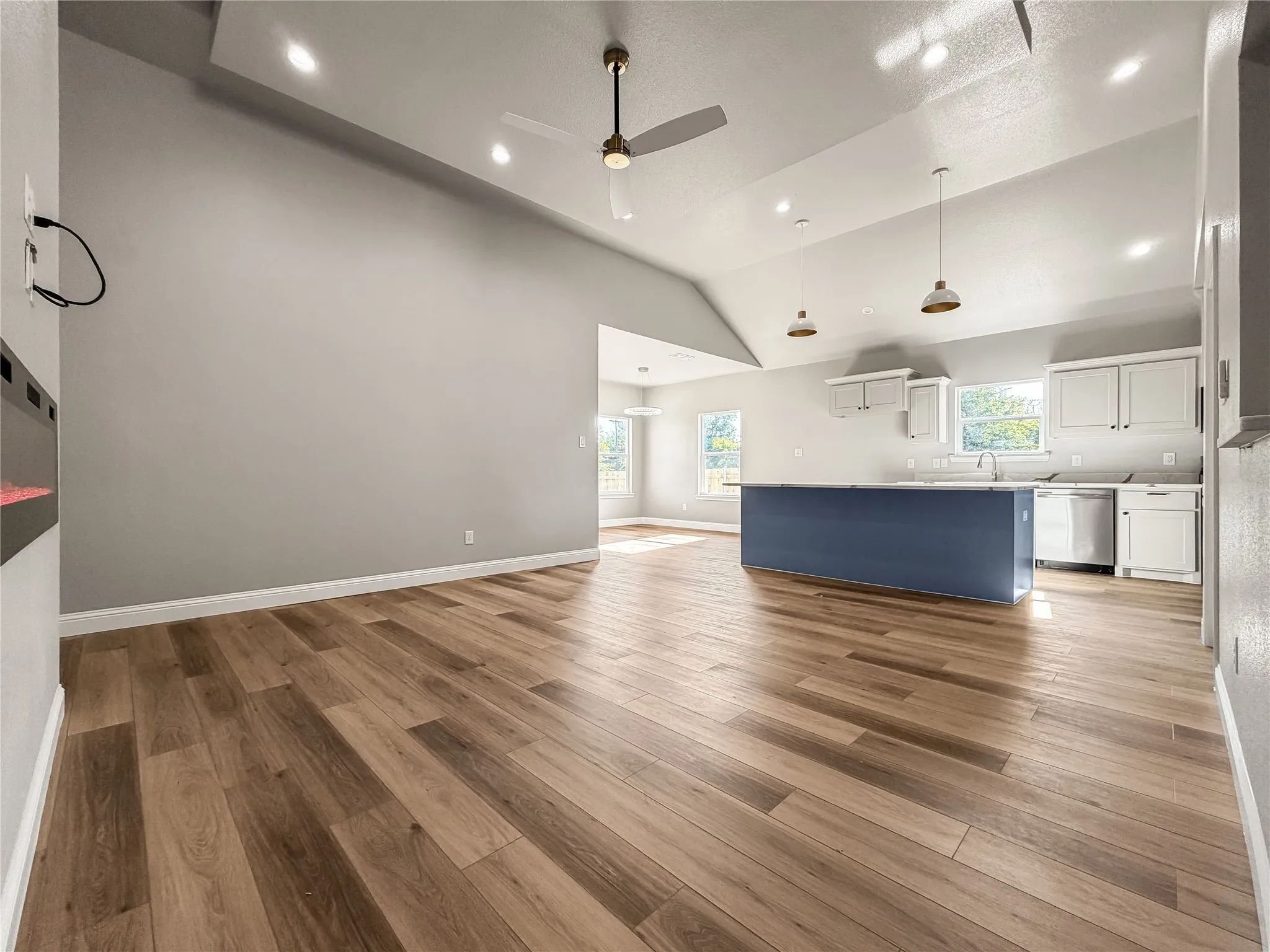 Open-concept living space featuring wood-finish flooring, vaulted ceilings, and recessed lighting