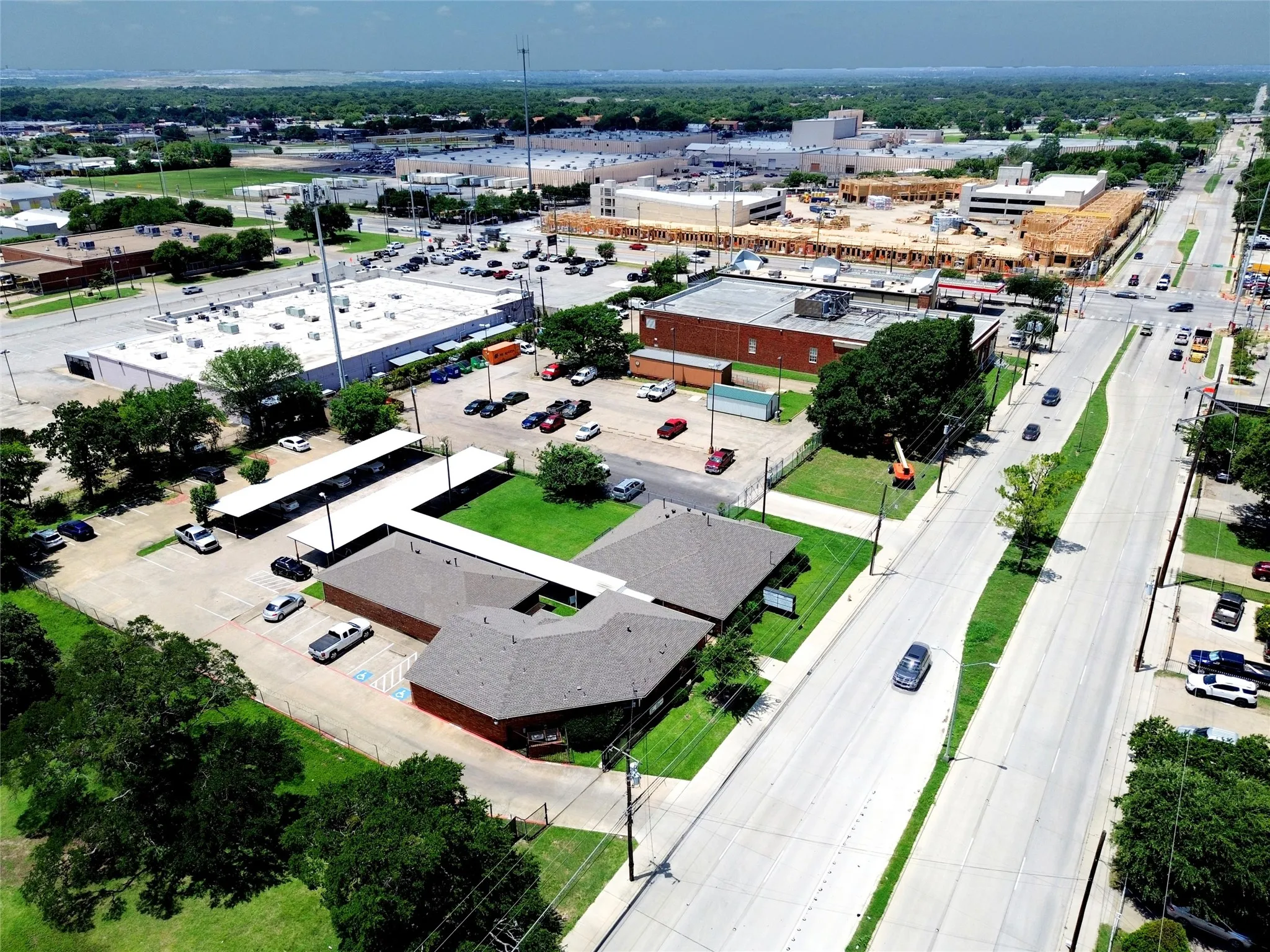 View of the building, parking lot and covered parking and walks.  Note SW corner is a new apartment complex under construction.