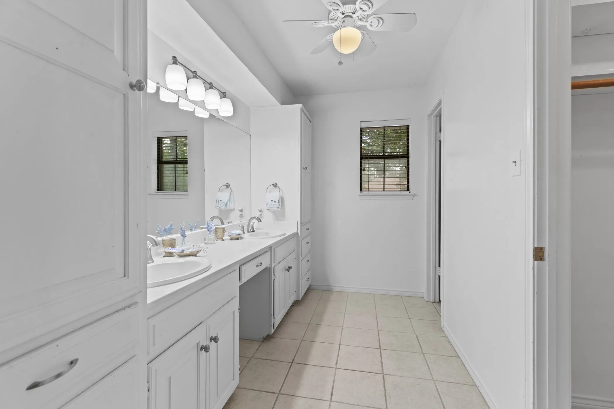 Bathroom featuring a dual vanity with white cabinetry, integrated sinks, and a large wall mirror