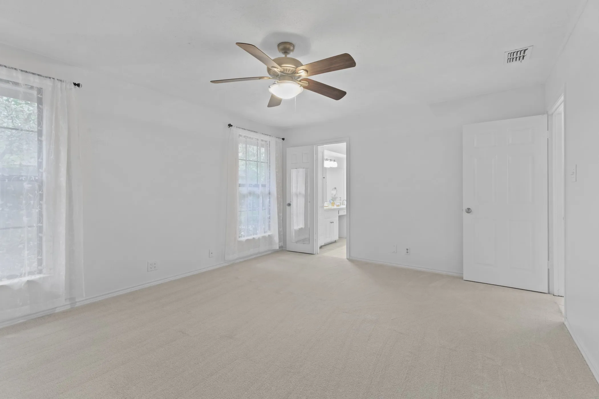Spacious room with light-toned carpeting and white walls