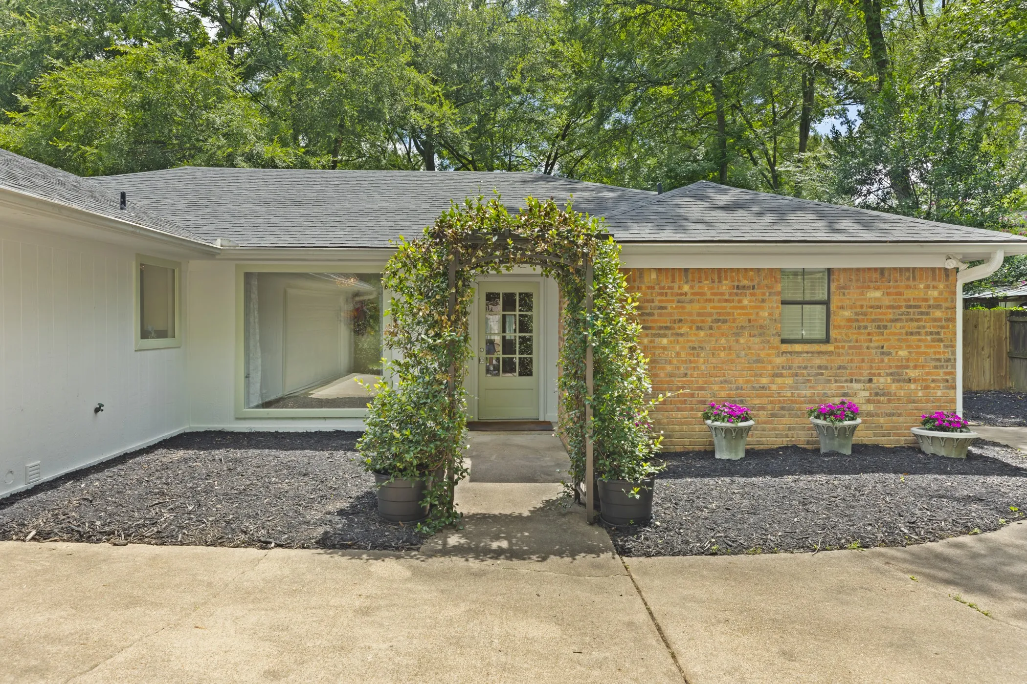 Front entry with a decorative arbor, full-light door, and an expansive picture window