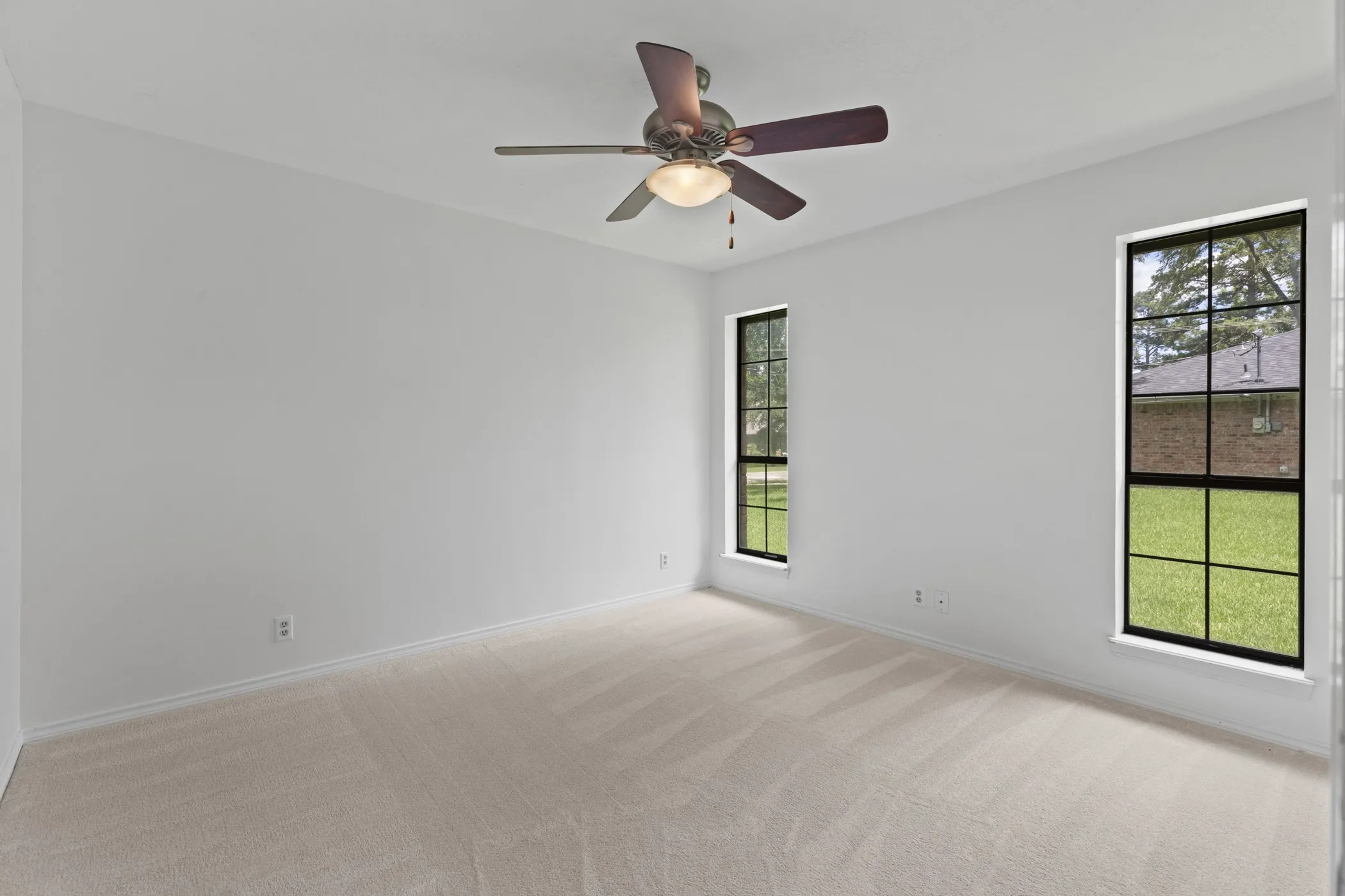 Spacious room featuring neutral carpeting, light-toned walls, and a ceiling fan with integrated lighting