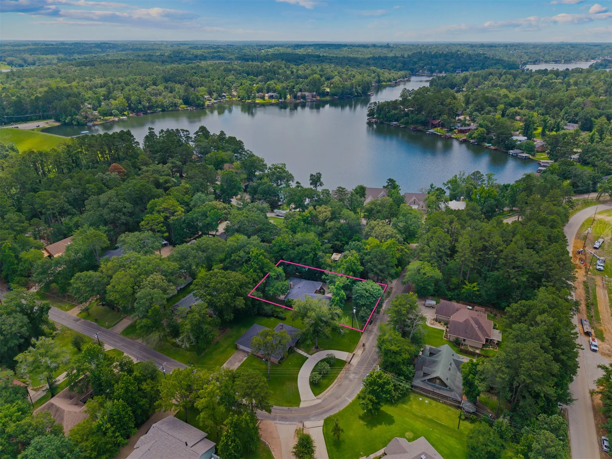 Aerial perspective showcasing a property with mature tree cover and proximity to a large body of water