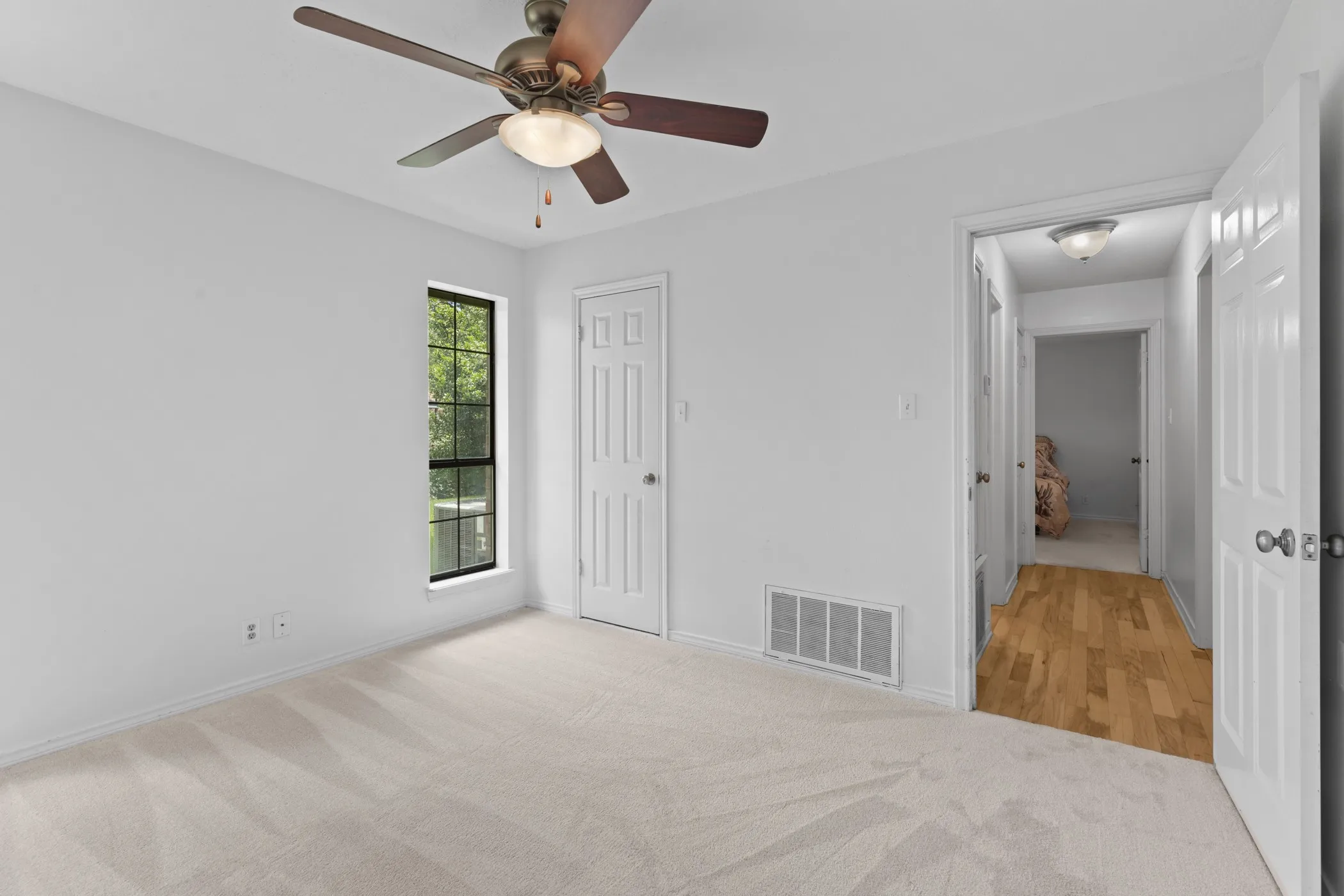 Carpeted room featuring a ceiling fan with integrated lighting, a multi-pane window, and white paneled doors