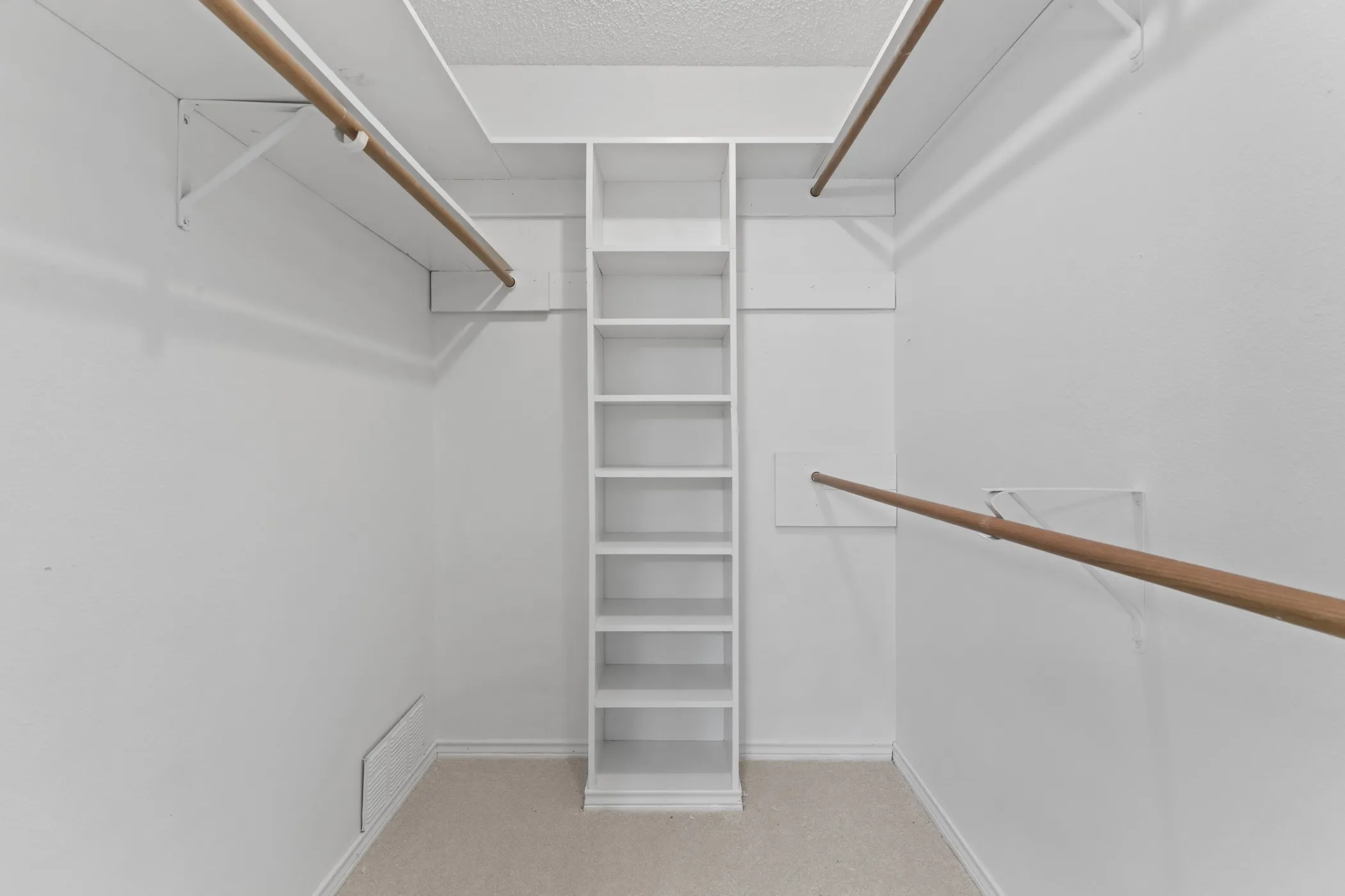 Walk-in closet featuring built-in shelving, multiple hanging rods, white walls, and carpet flooring