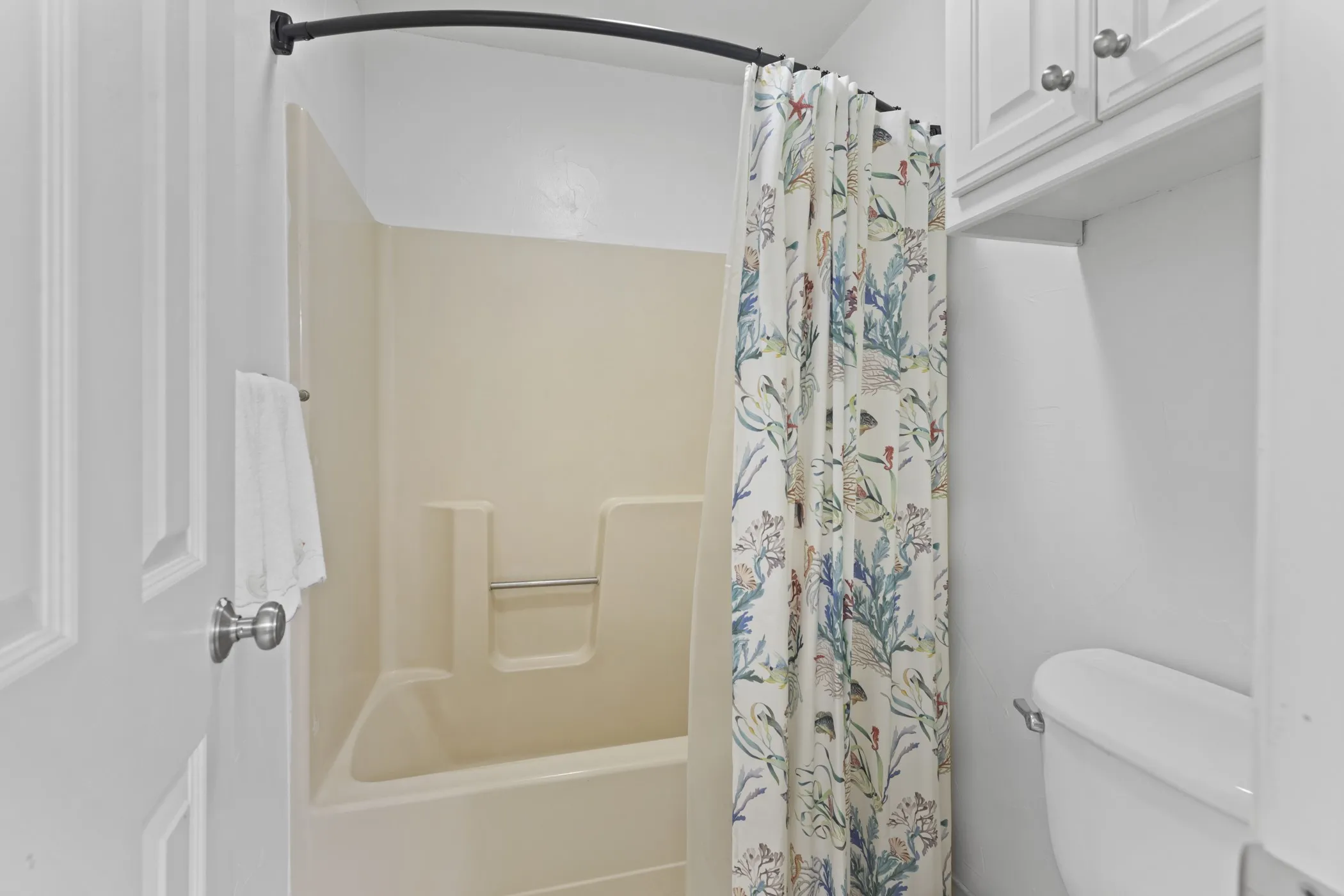 Tub/shower combination featuring a curved shower rod and integrated shelving