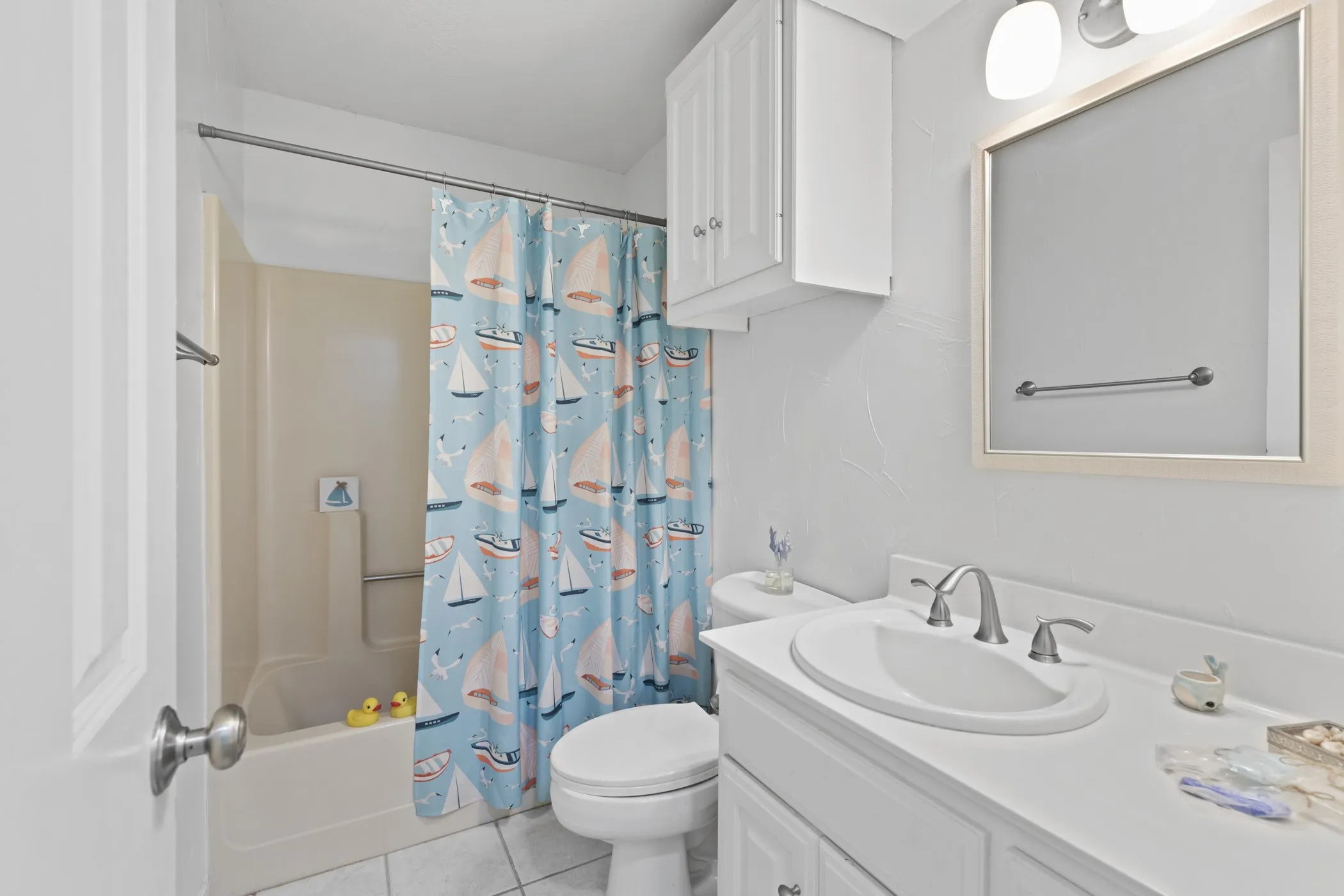 Bathroom featuring a white vanity with an integrated sink, brushed nickel faucet, and framed mirror