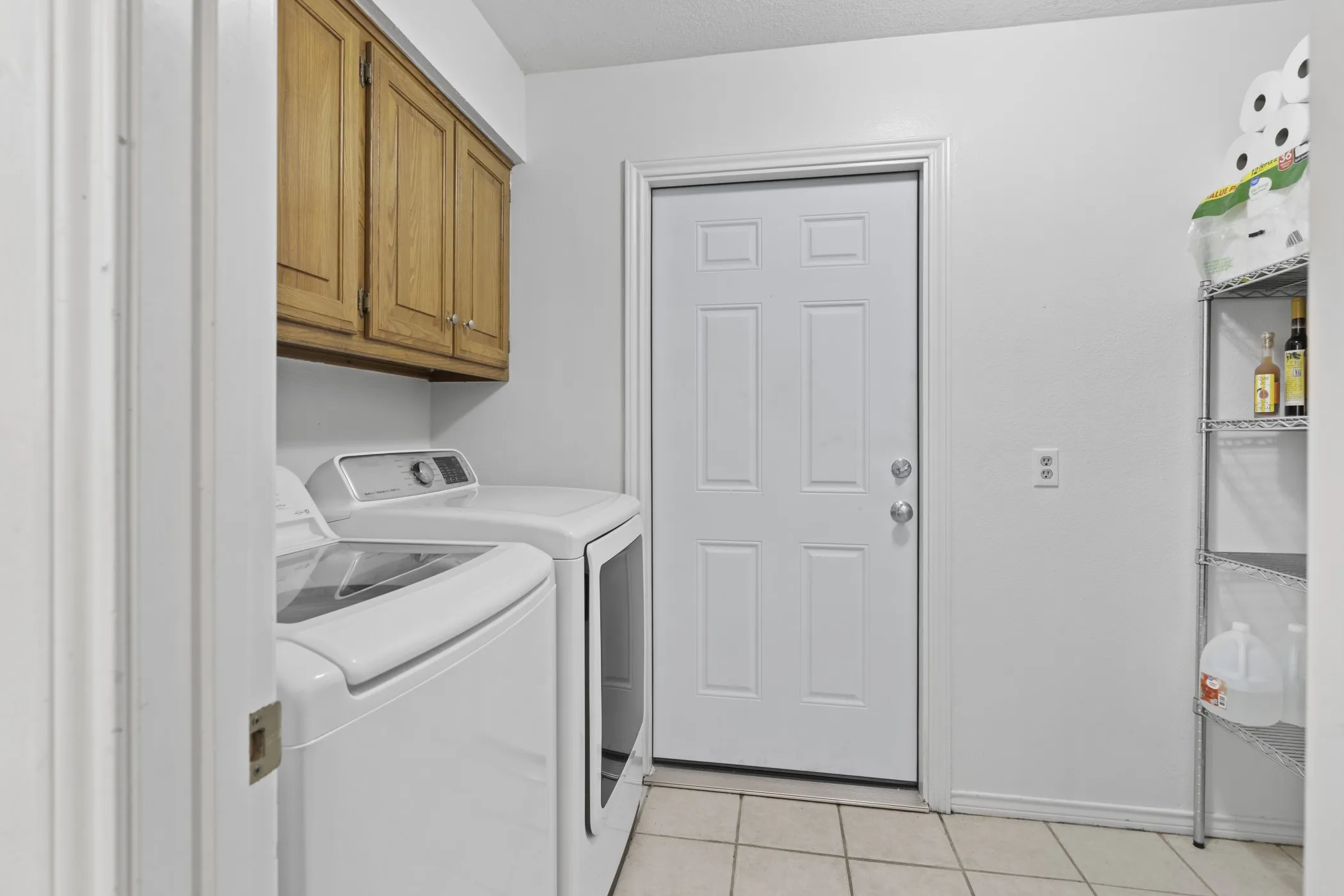 Utility area featuring wood cabinetry, white six-panel door, and tiled flooring
