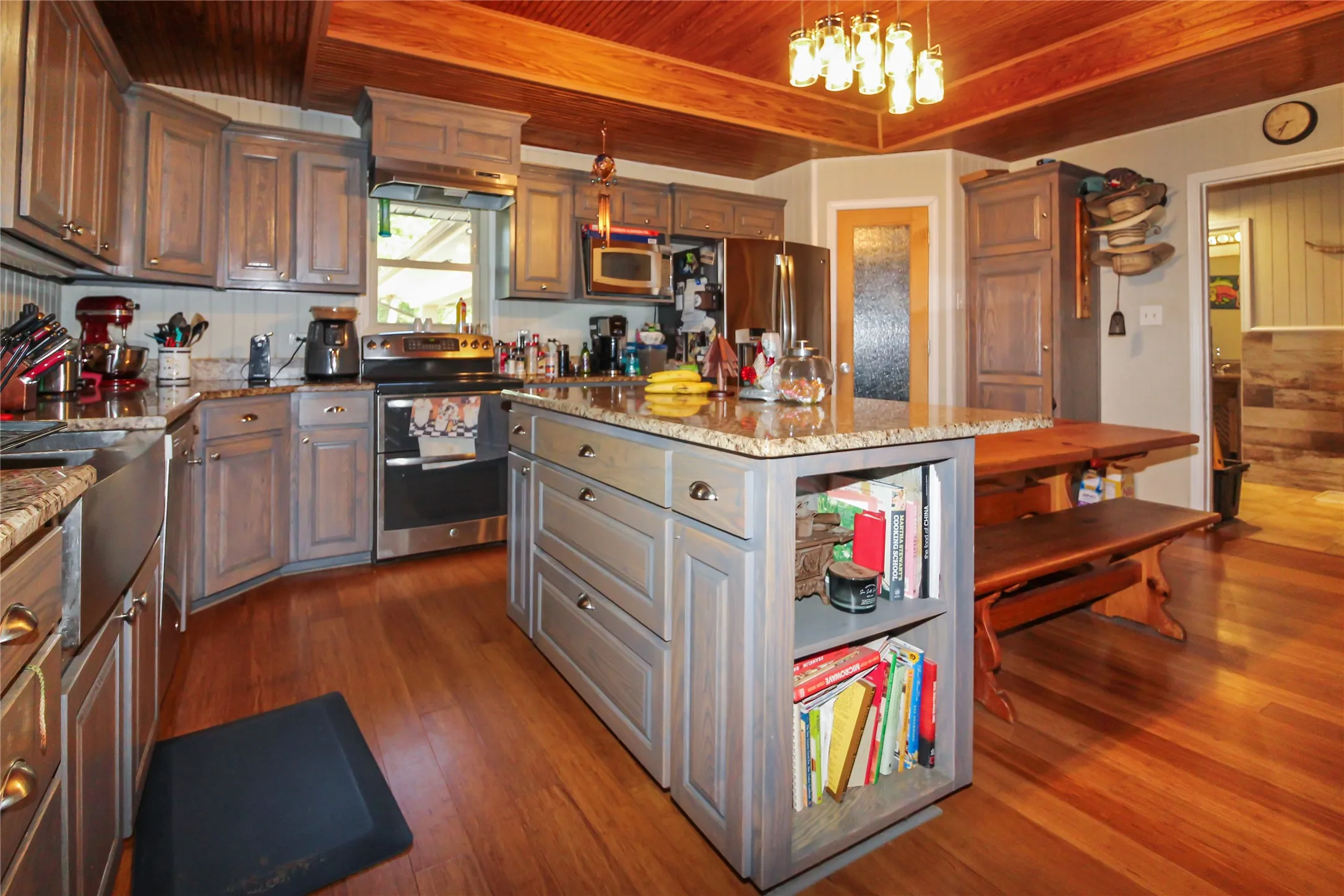 Kitchen featuring wood-finish flooring, a wood-paneled ceiling with exposed beams, gray cabinetry, granite countertops, and a stainless steel farmhouse sink