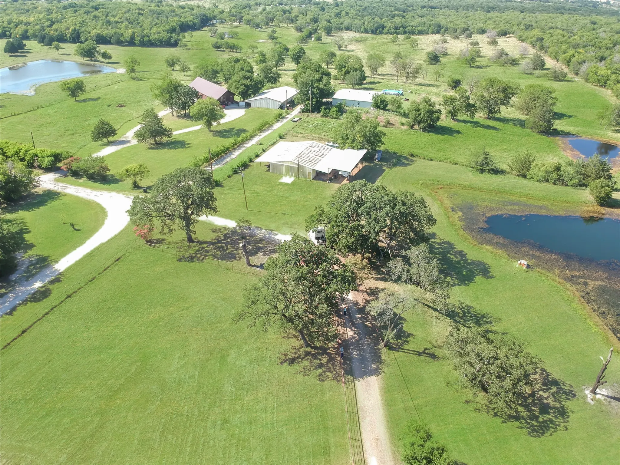 Expansive property featuring verdant green acreage, multiple buildings, and two ponds