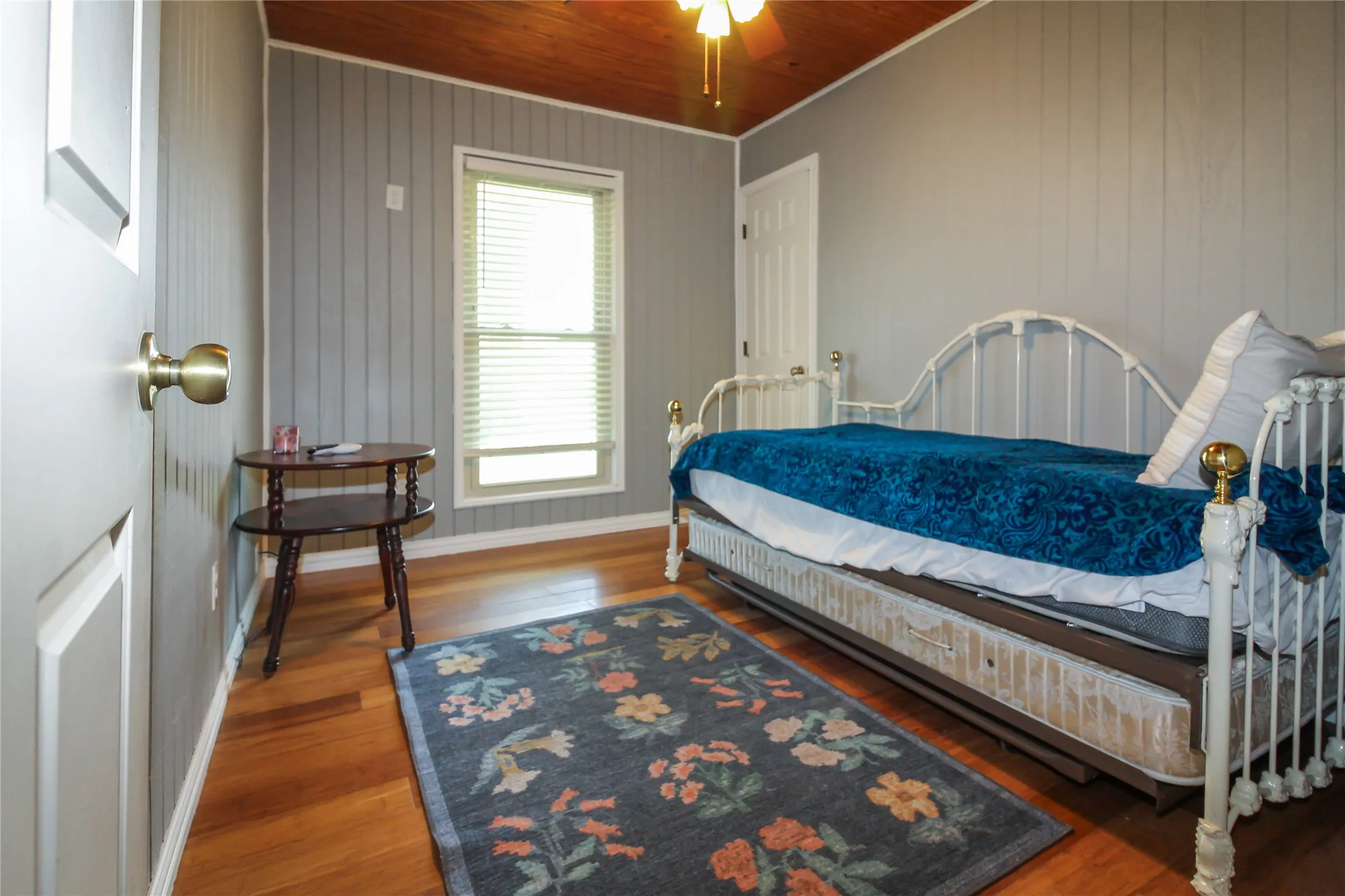Room featuring wood-finish flooring, vertical paneling on walls, and a natural wood-plank ceiling
