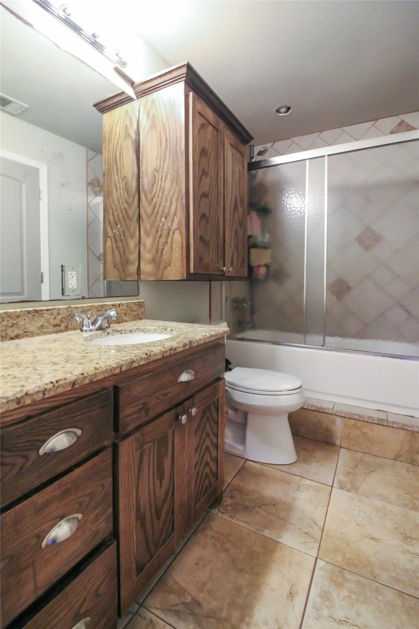 Bathroom featuring a single vanity with a granite countertop, undermount sink, and wood-finish cabinetry