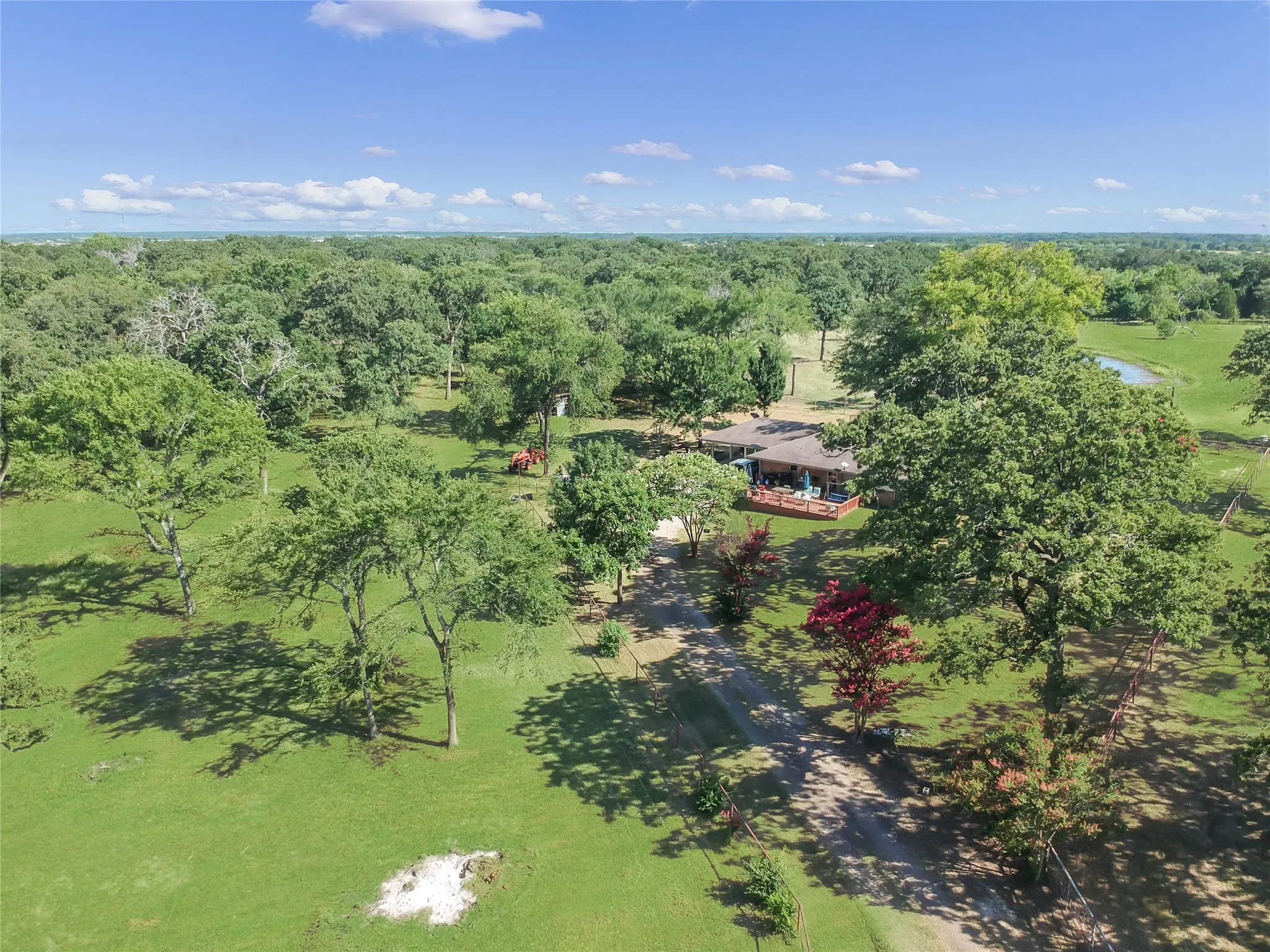 Expansive property featuring a single-story residence with a covered porch, set amidst abundant mature trees