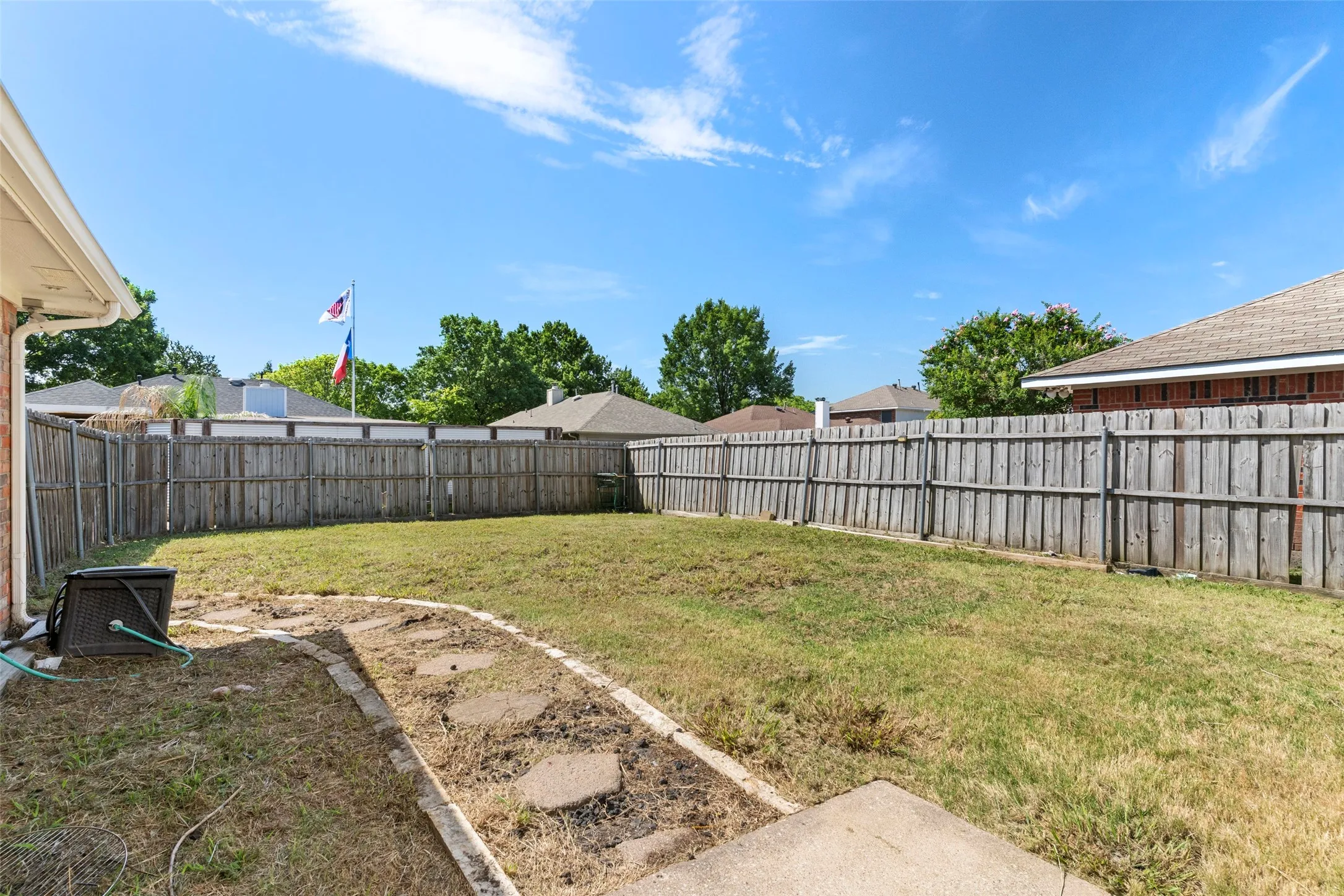 Spacious backyard featuring a full perimeter wooden privacy fence and a concrete patio