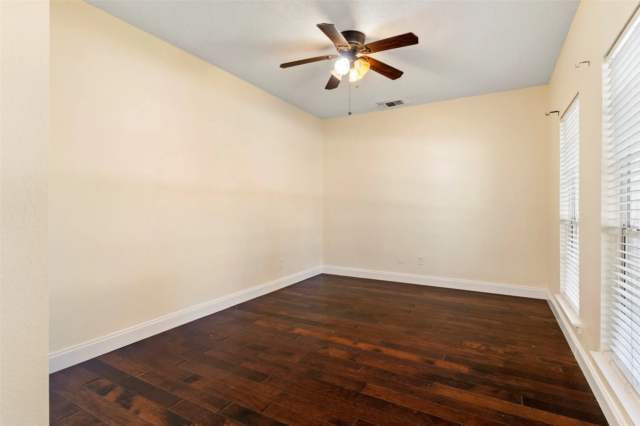 Room featuring wood-finish flooring, light-toned walls, and white baseboards