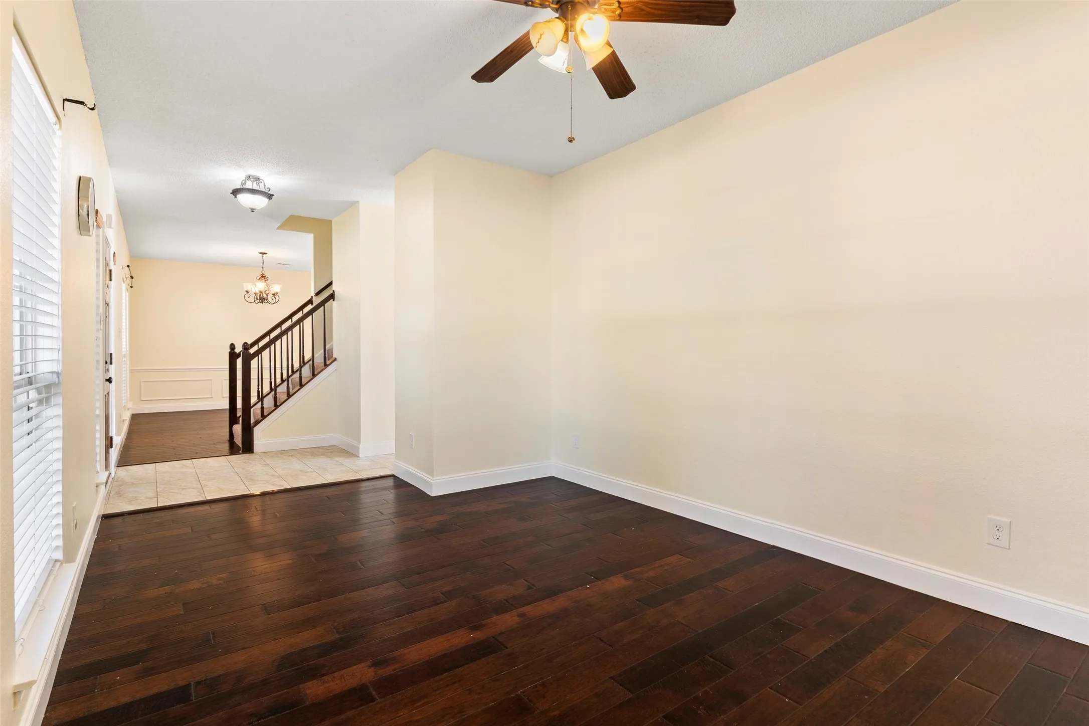 Spacious room featuring dark wood-finish flooring, light-colored walls, and a ceiling fan with integrated​​‌​​​​‌​​‌‌​‌‌​​​‌‌​‌​‌​‌​​​‌​​ lighting