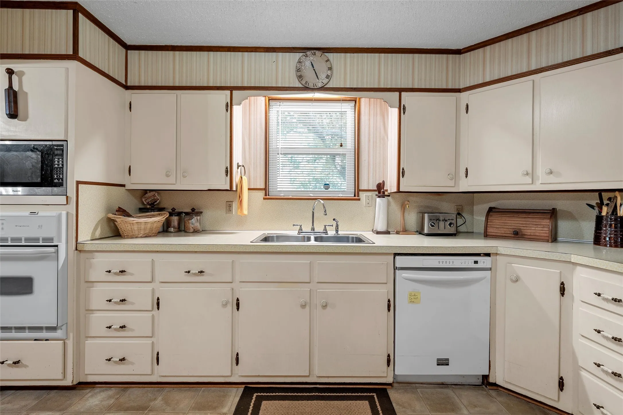 Kitchen featuring white cabinetry with matching hardware, a built-in microwave, an integrated oven, and a double basin sink
